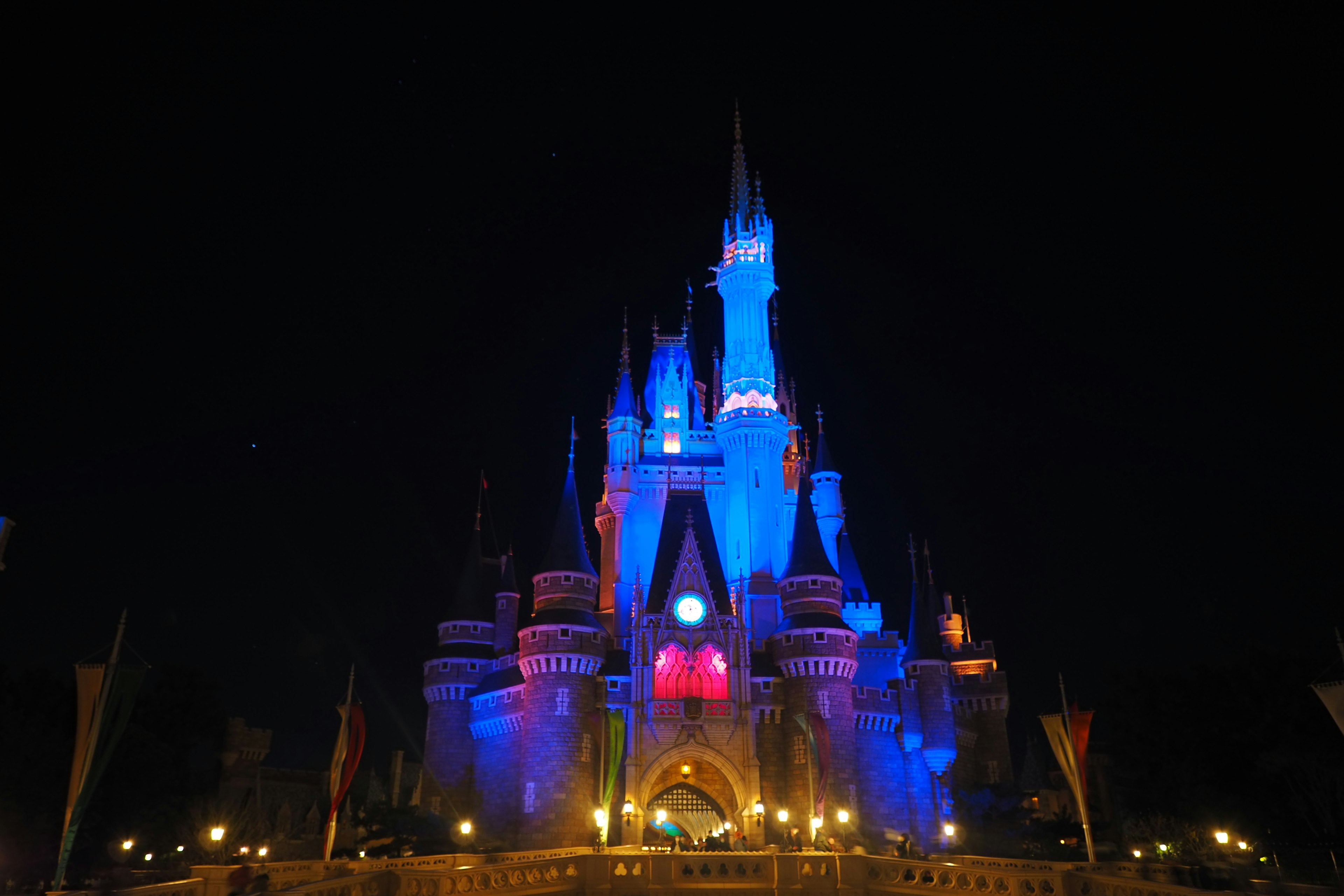 Castillo de Cenicienta en el parque Disney iluminado en luces azules y rojas por la noche