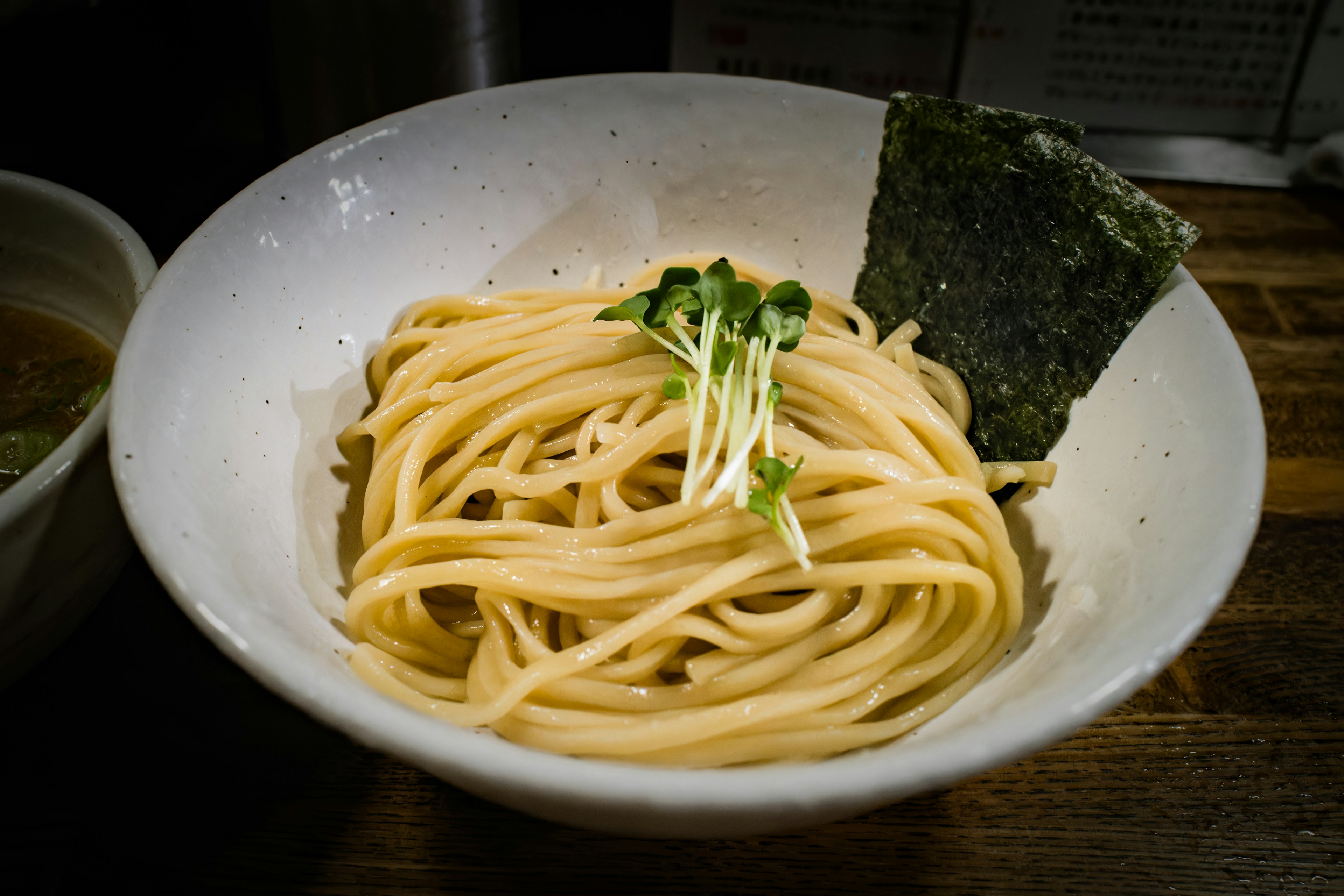 A bowl of thin pasta topped with sprouts and a piece of seaweed