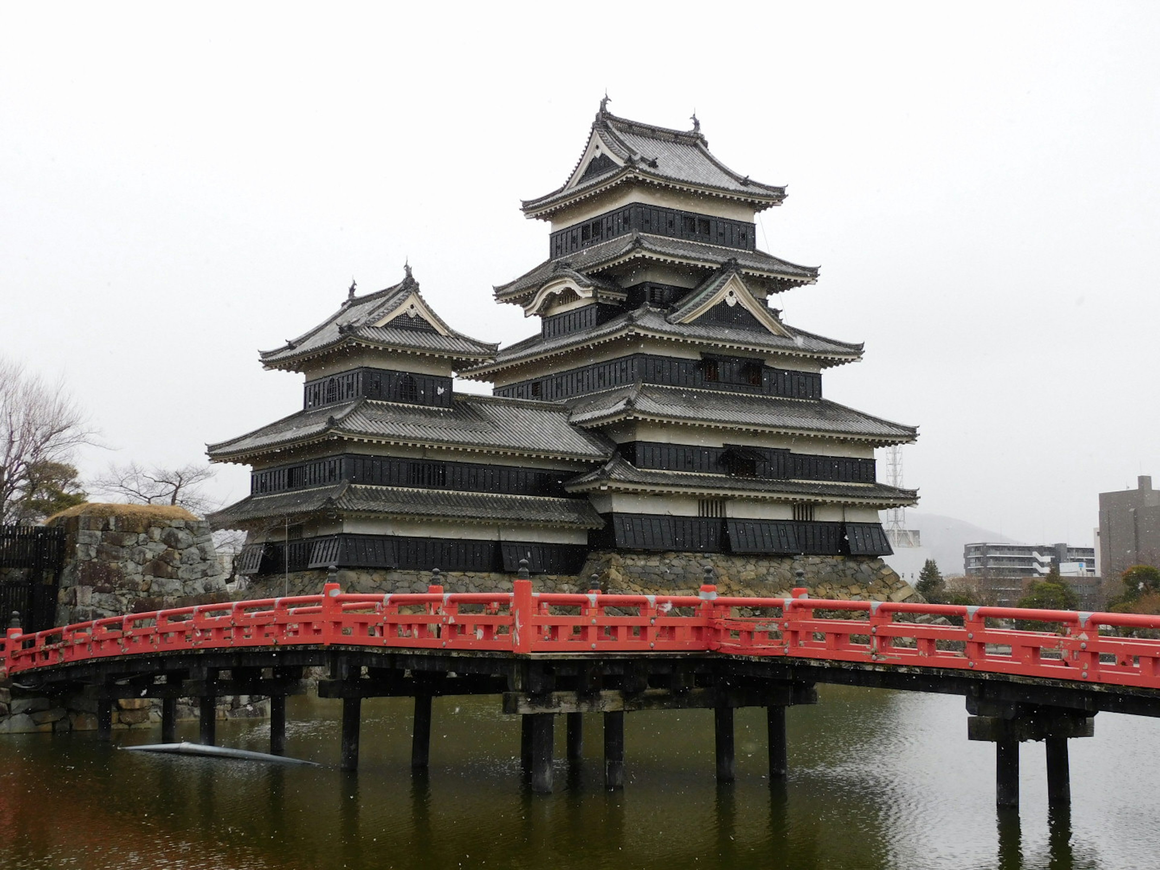 Malersiche Ansicht von Matsumoto Schloss mit einer roten Brücke und ruhigem Wasser