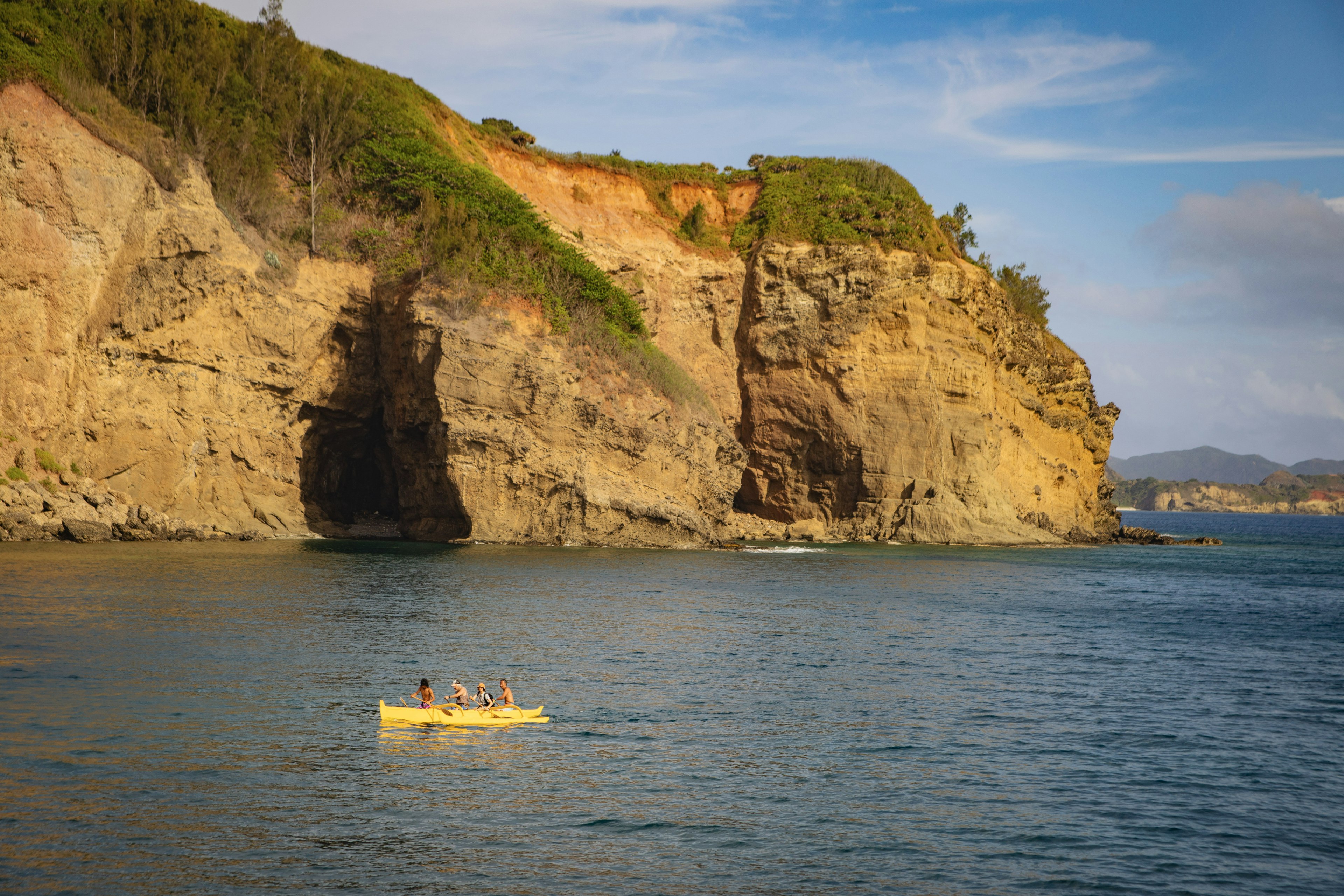 Kayakers on the water near a rocky cliff