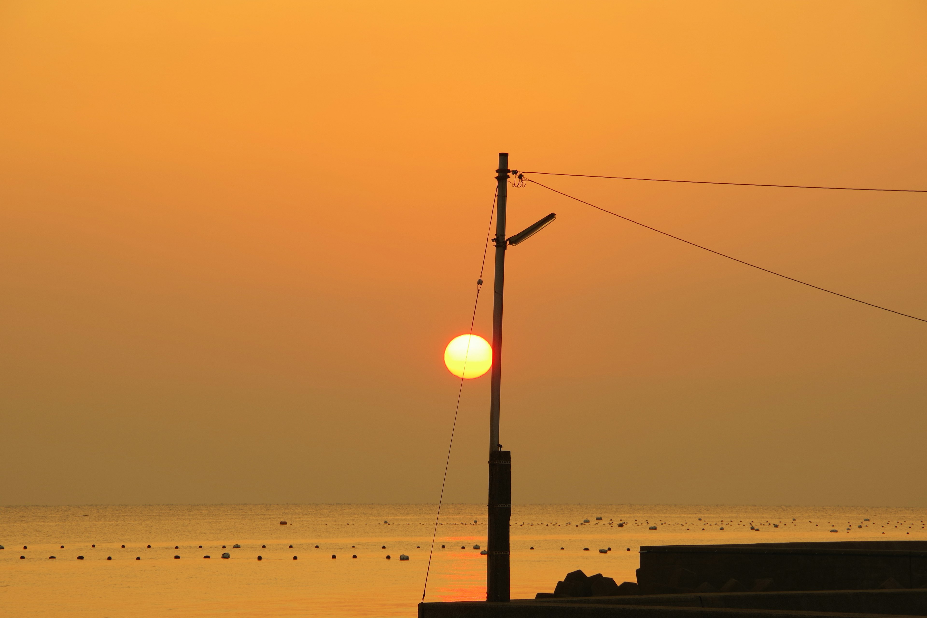 Coucher de soleil sur l'océan avec un ciel orange et un poteau électrique