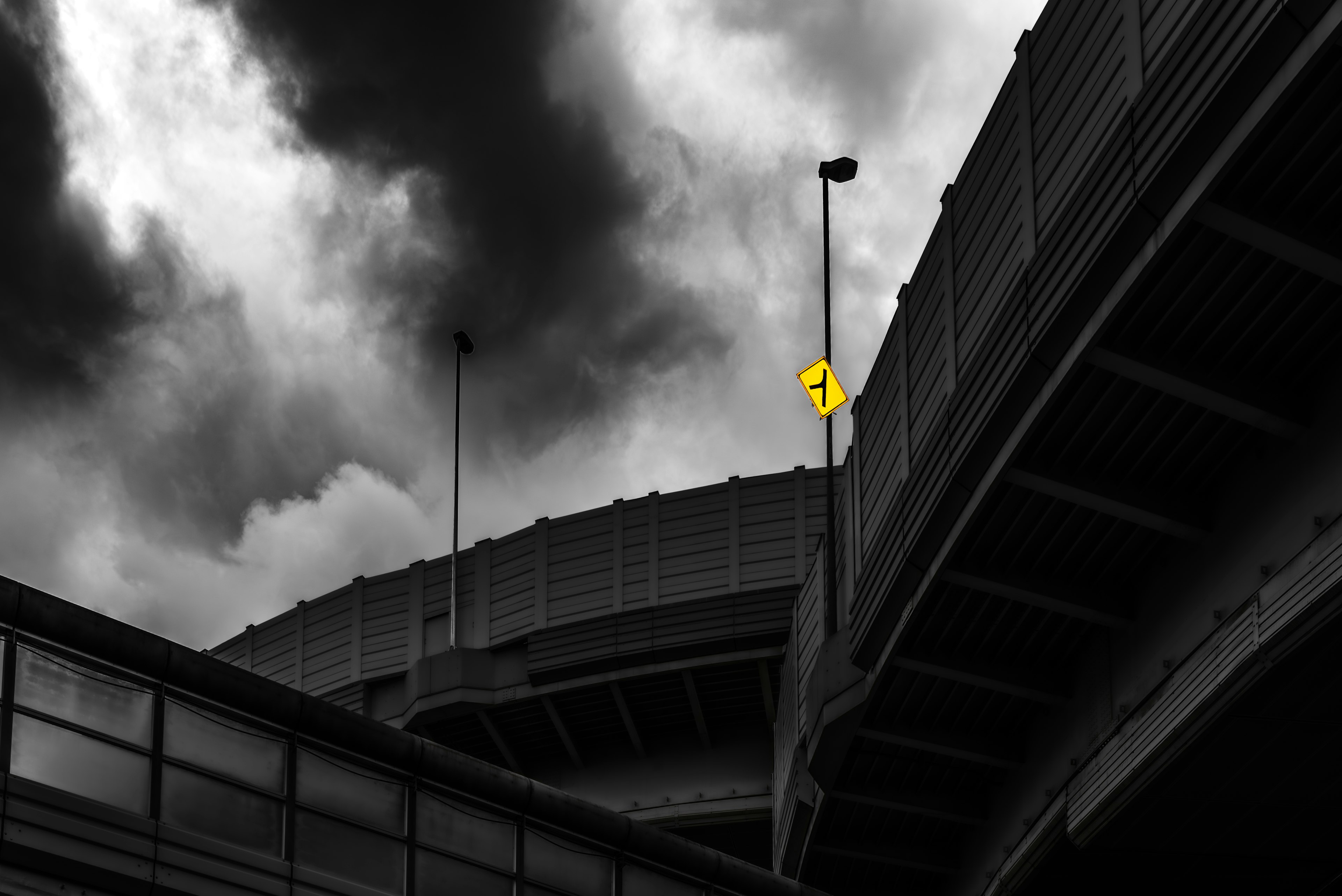 Überführung unter dunklen Wolken mit einem gelben Schild