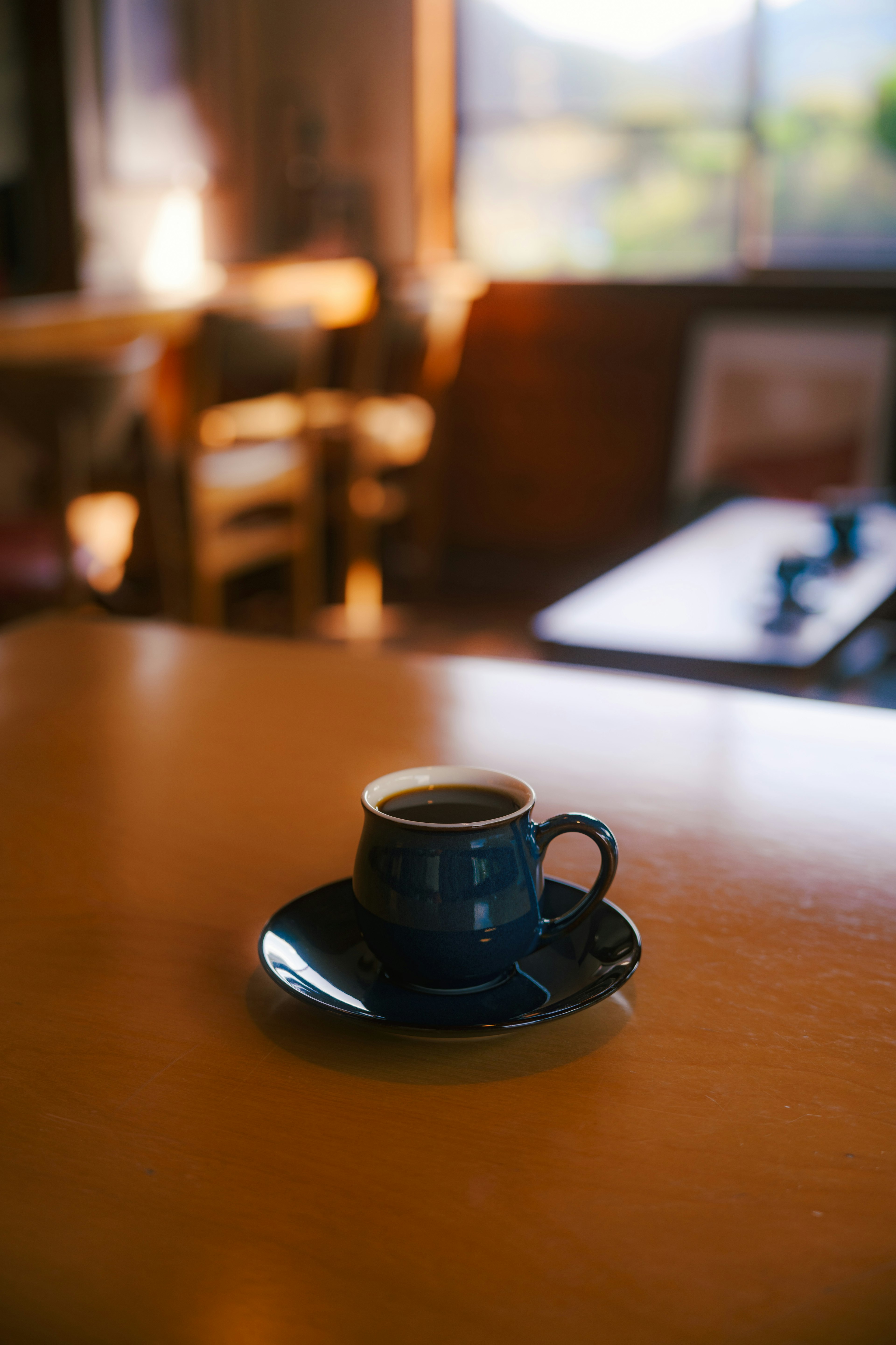 Sebuah cangkir kopi biru di atas piring di meja kayu