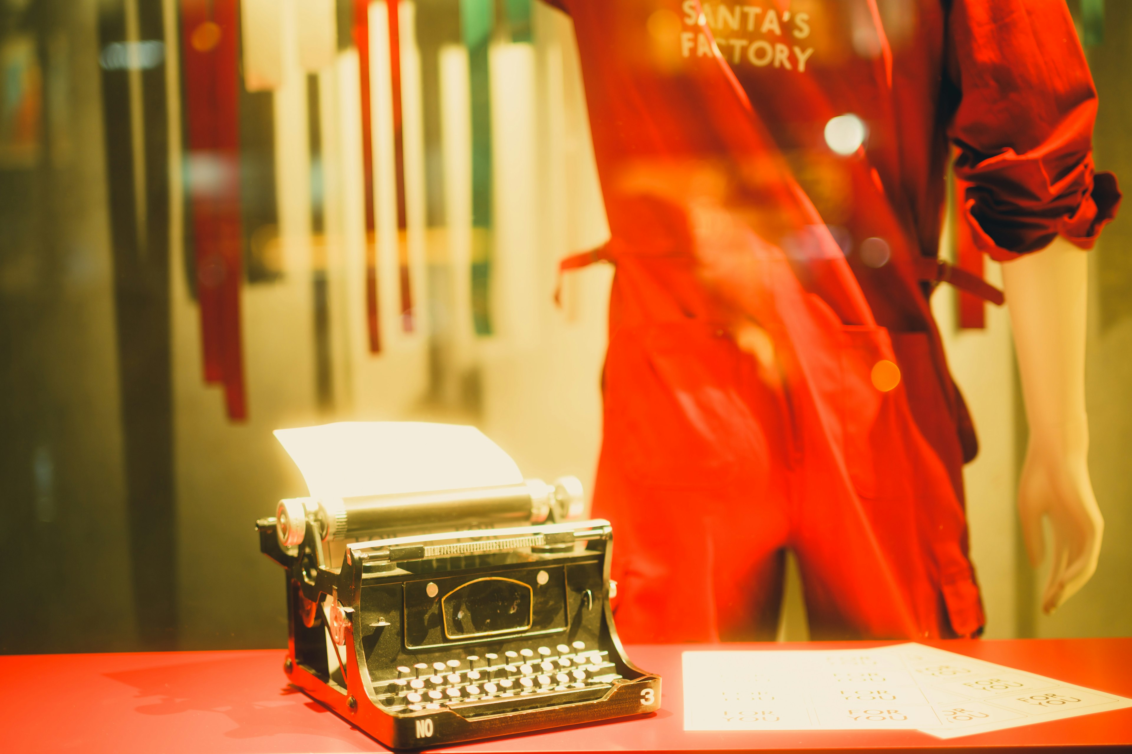 Vintage typewriter on red surface with a figure in red clothing representing Santa's workshop