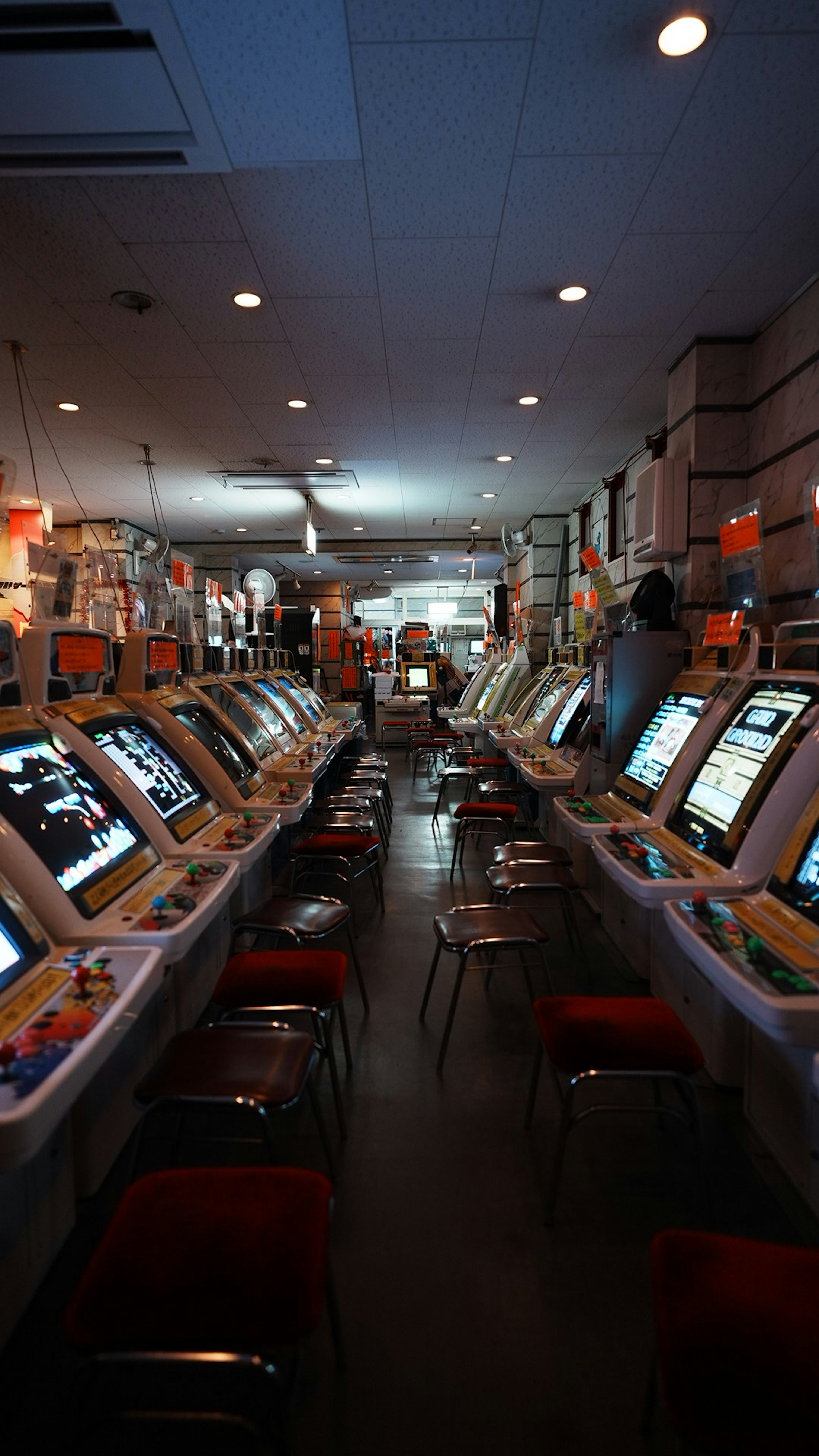 ゲーム機が並ぶ暗い部屋に赤い椅子