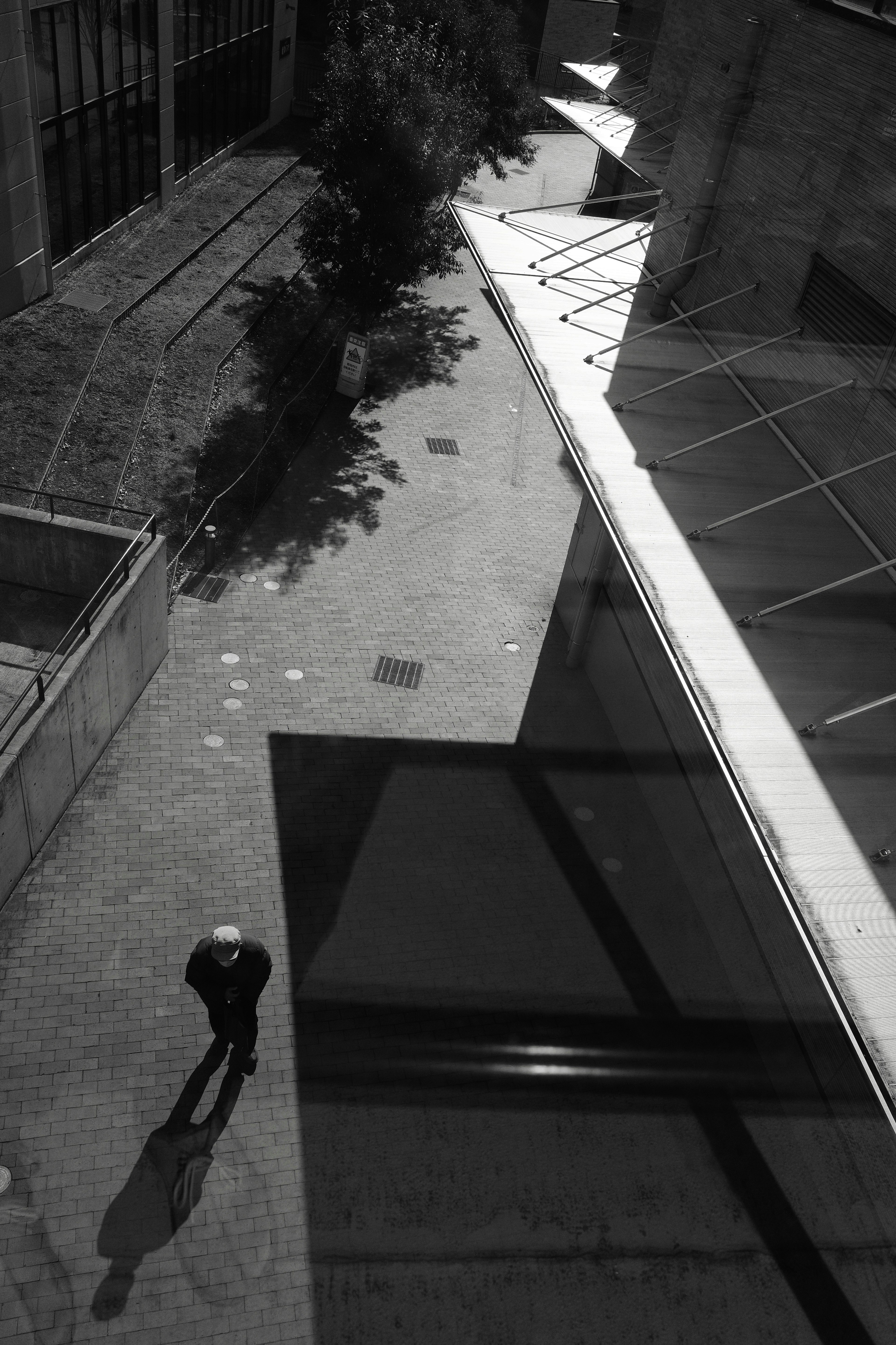 Una persona de pie en la sombra en una escena urbana en blanco y negro