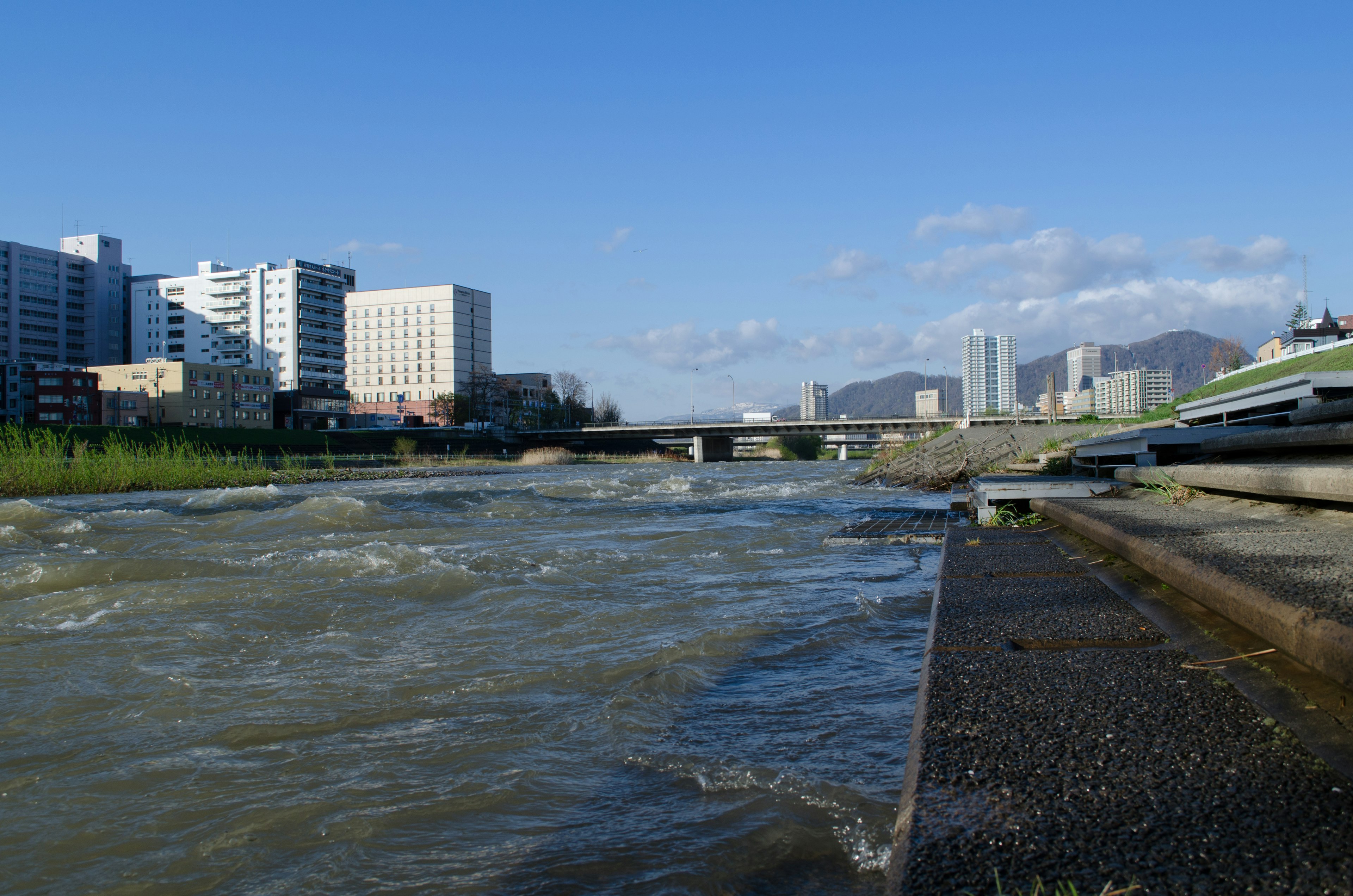 川の近くに立つビル群と青空が広がる風景