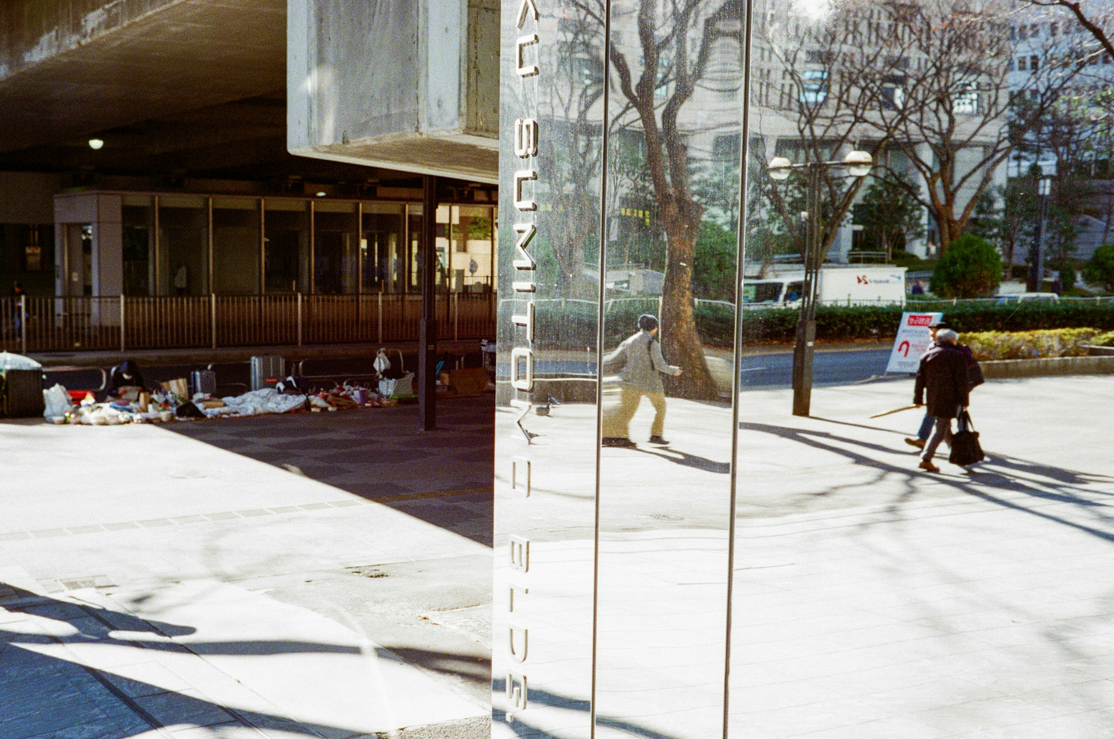 Stadtlandschaft mit einem reflektierenden Pfeiler und Menschen, die gehen