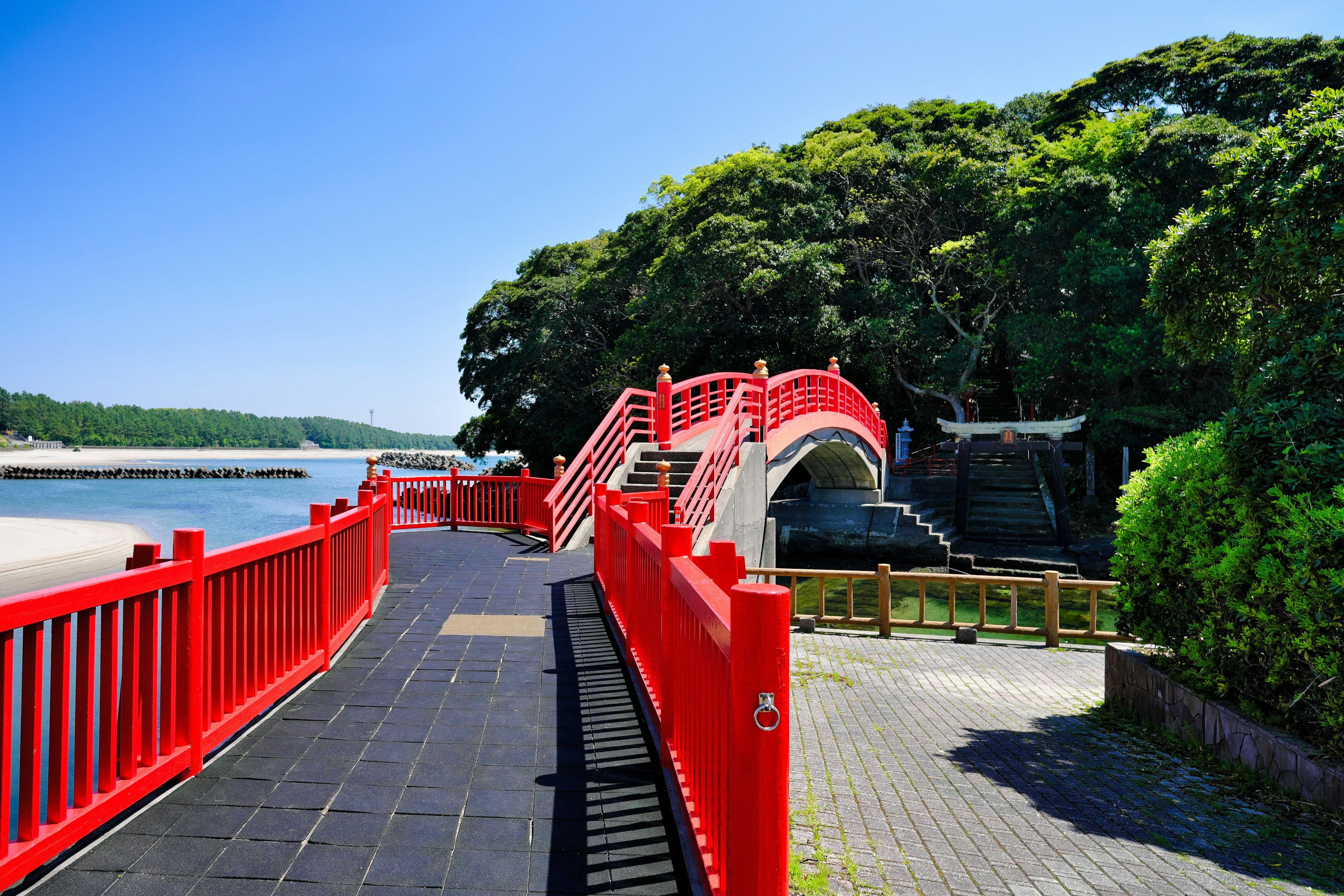 Scenic view of a red bridge and lush greenery by the coast