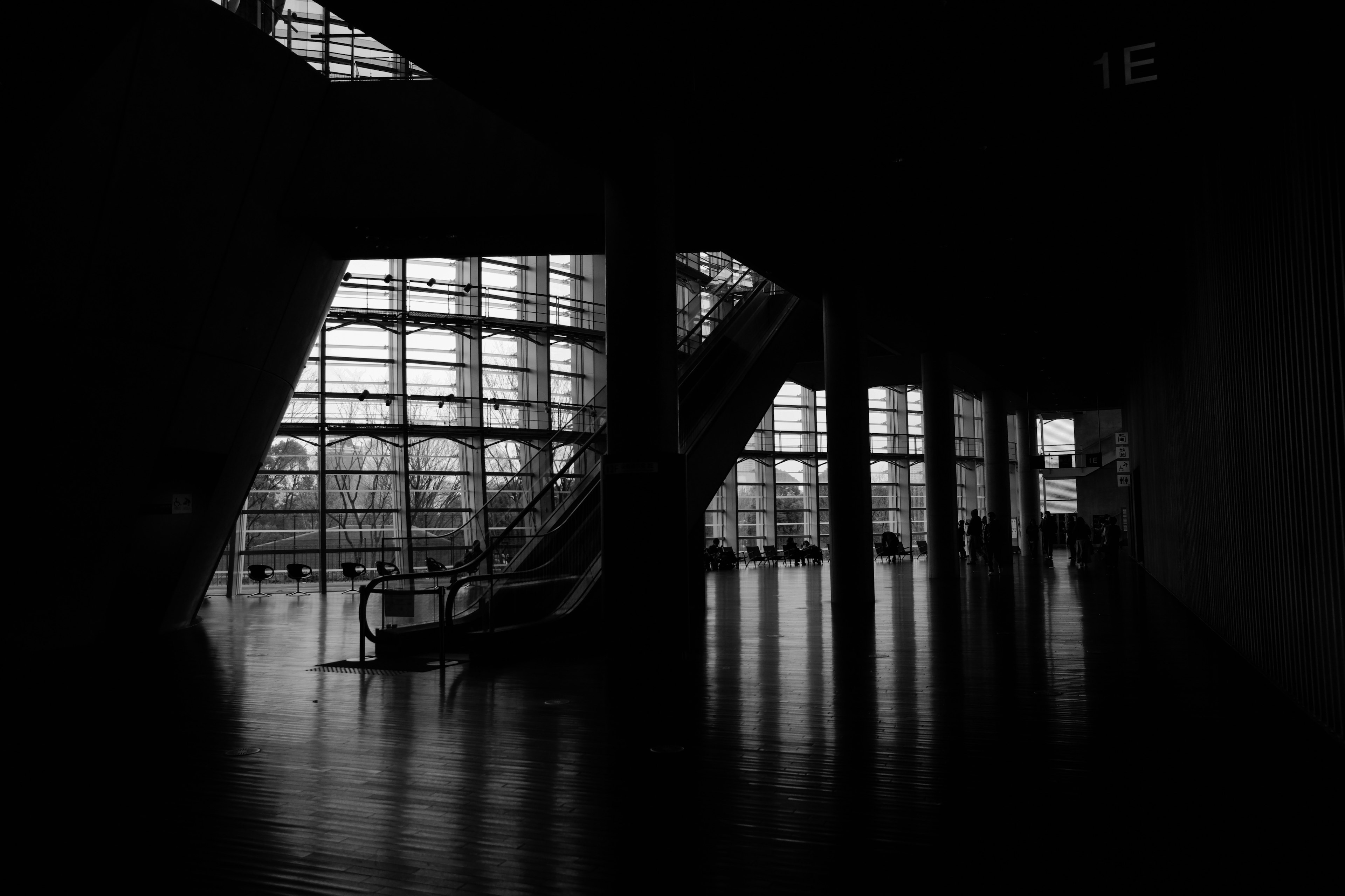 Intérieur d'un bâtiment moderne avec des murs en verre transparent, silhouette d'un escalier, éclairage tamisé