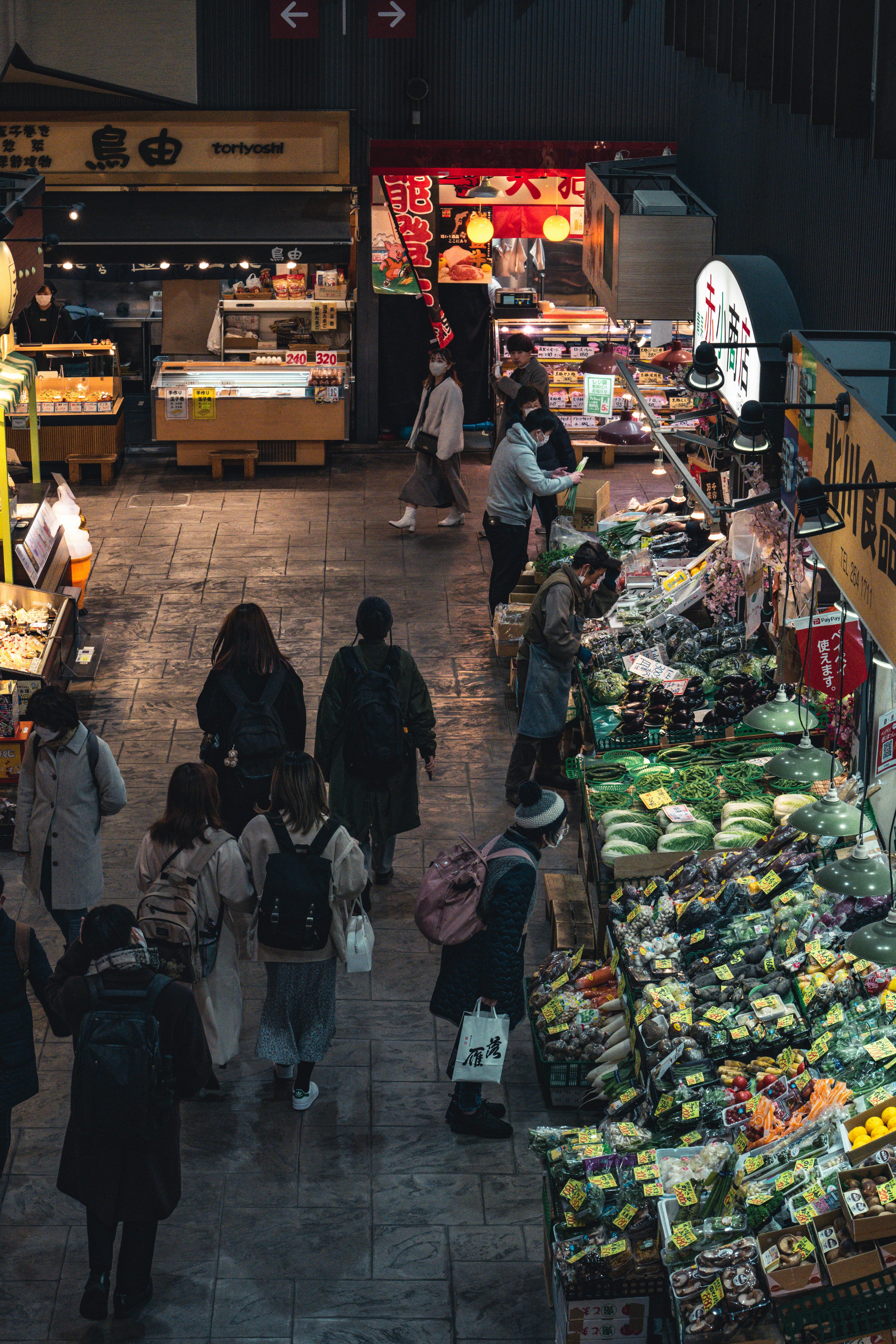 Indoor market scene with shoppers and fresh fruits and vegetables on display