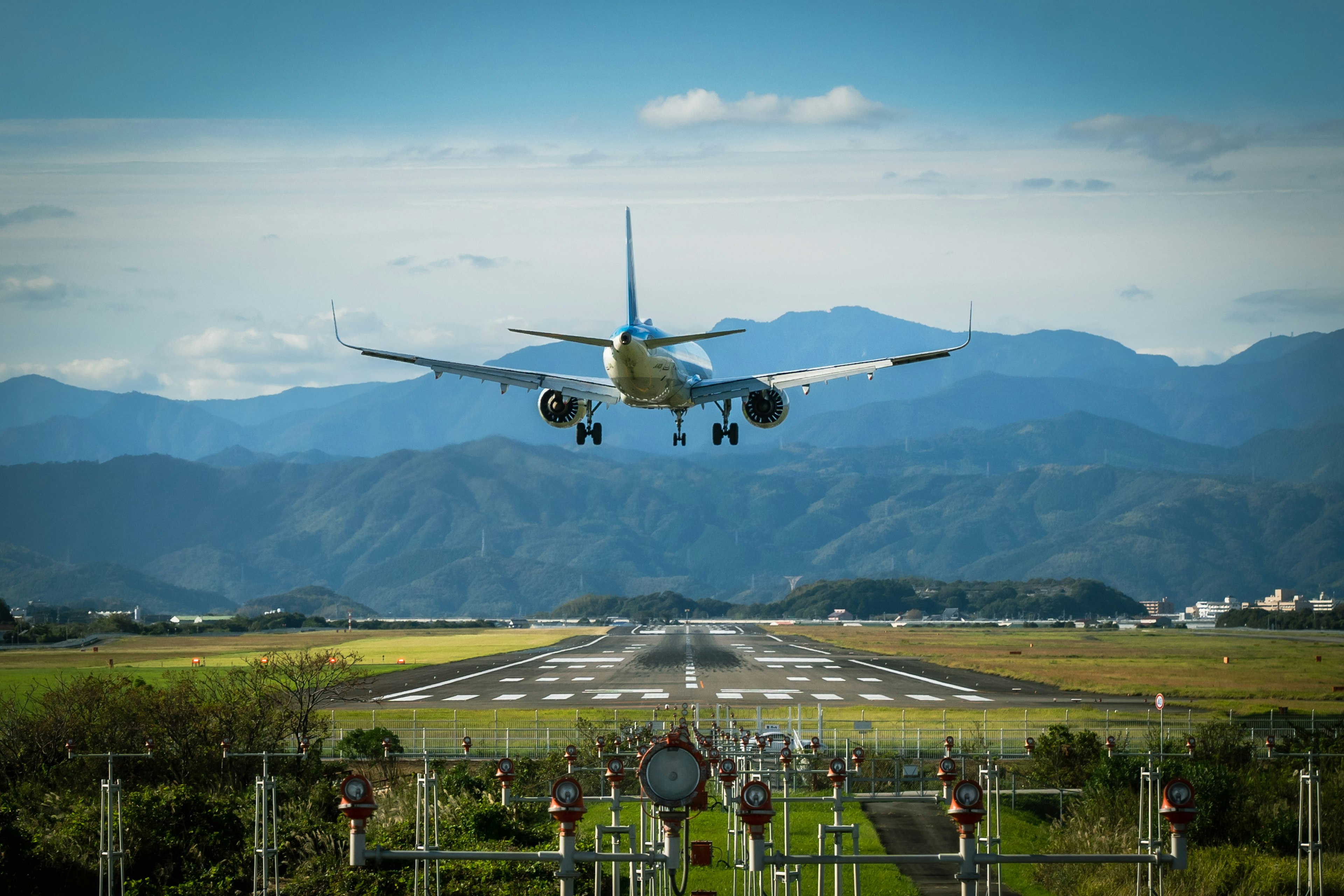 Avión aterrizando en la pista con montañas y cielo azul de fondo