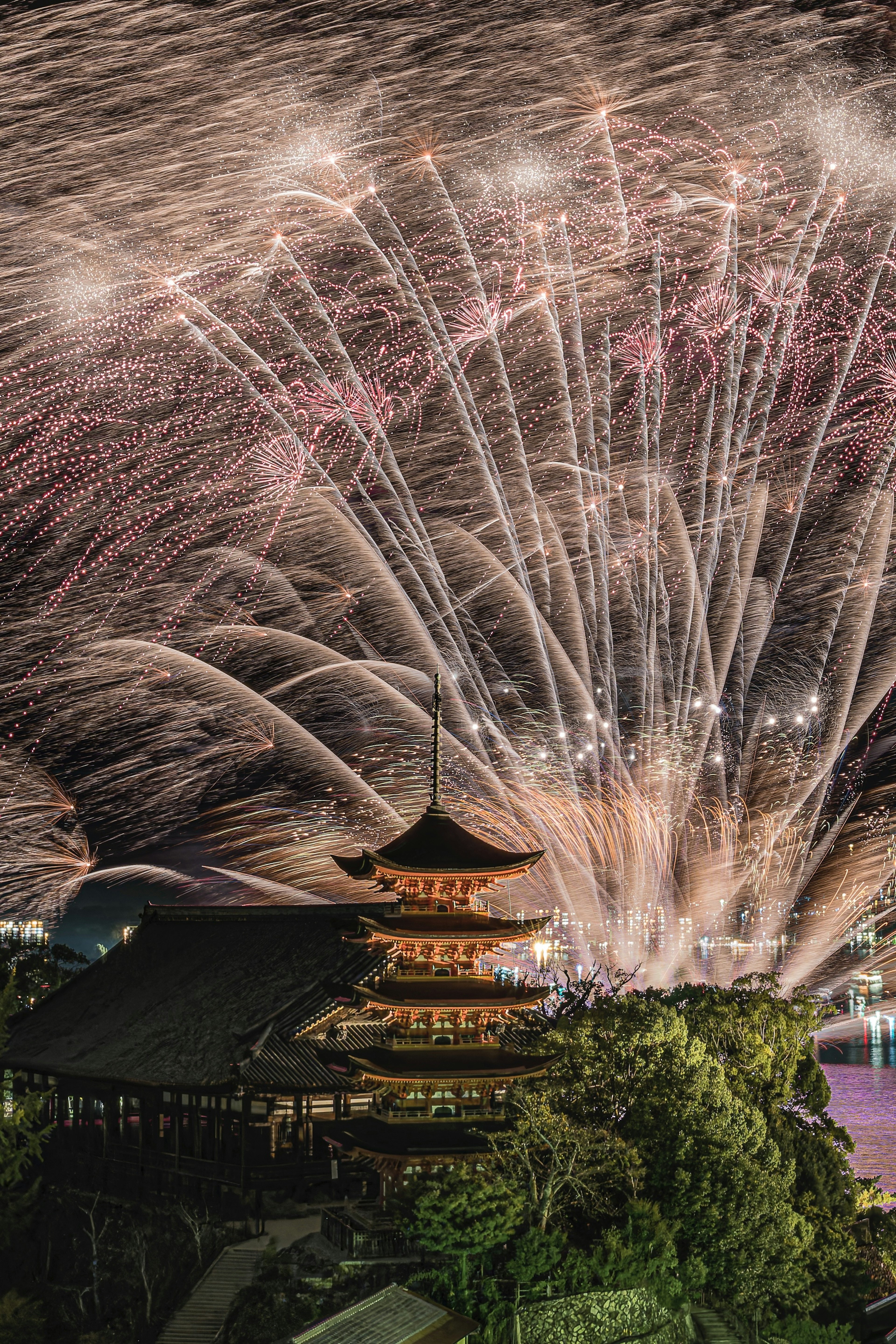 美麗的煙火照亮了夜空，傳統的日本建築在下面