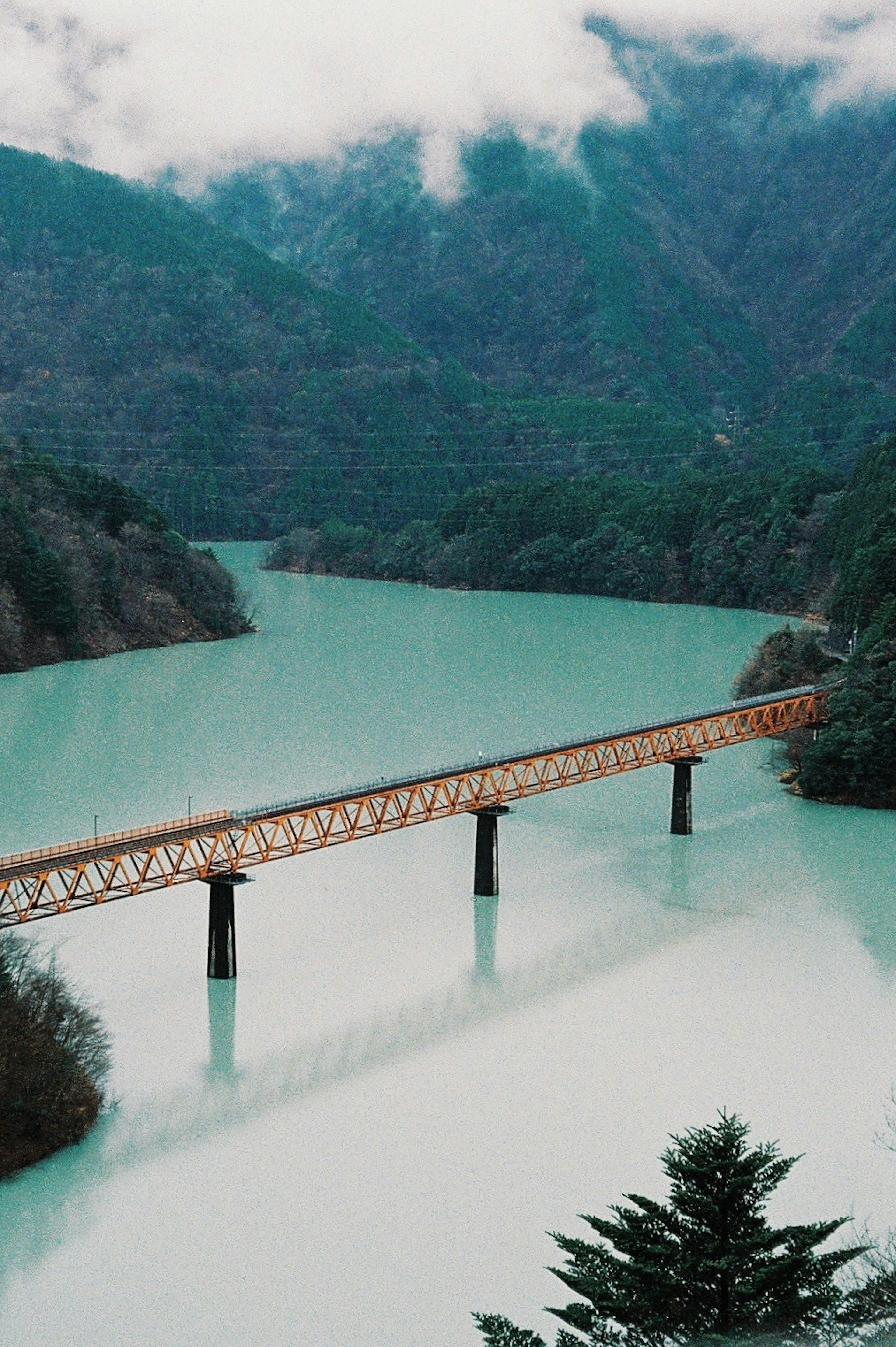 Pont en bois sur une eau turquoise avec des montagnes en arrière-plan