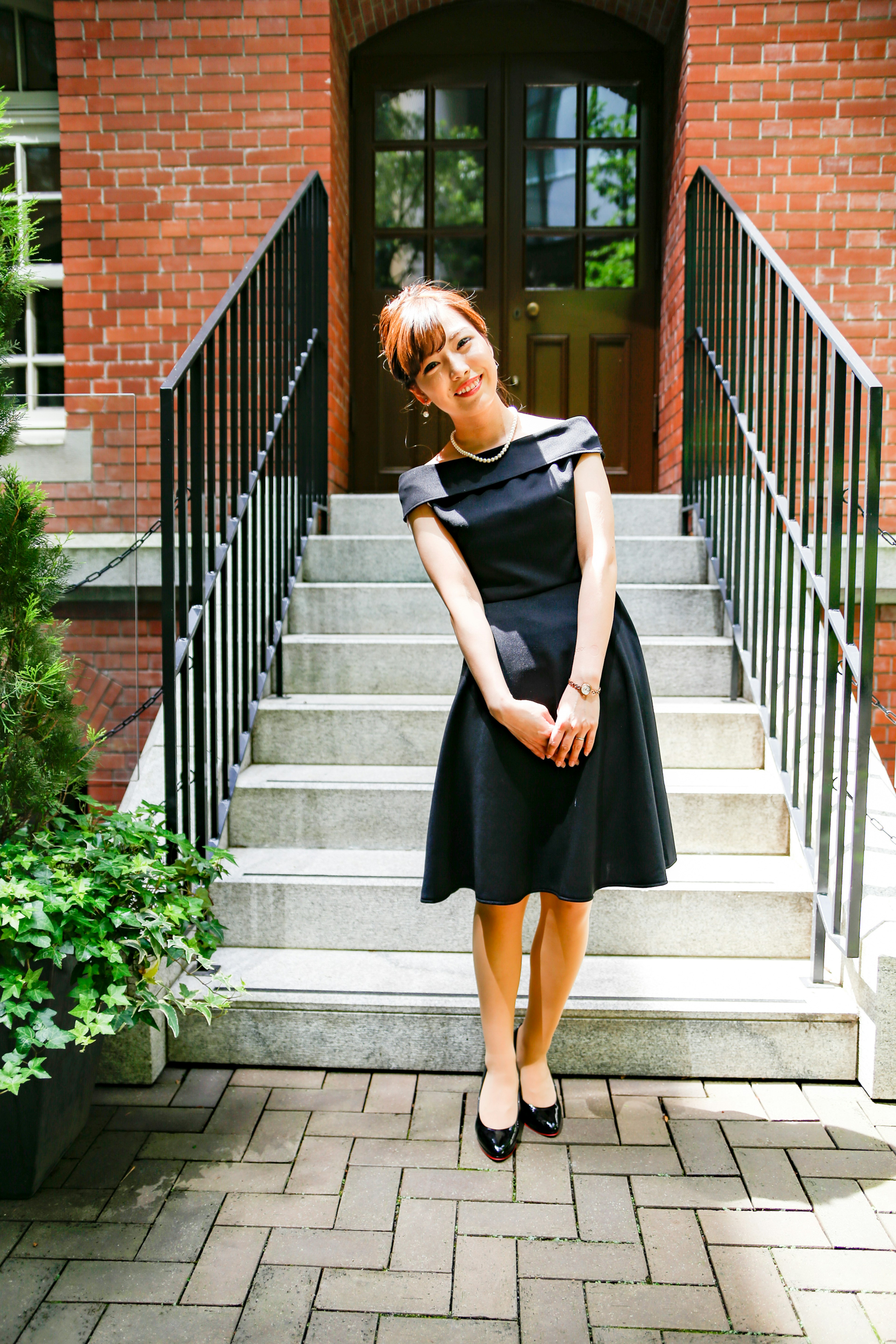 A woman in a black dress standing in front of stairs