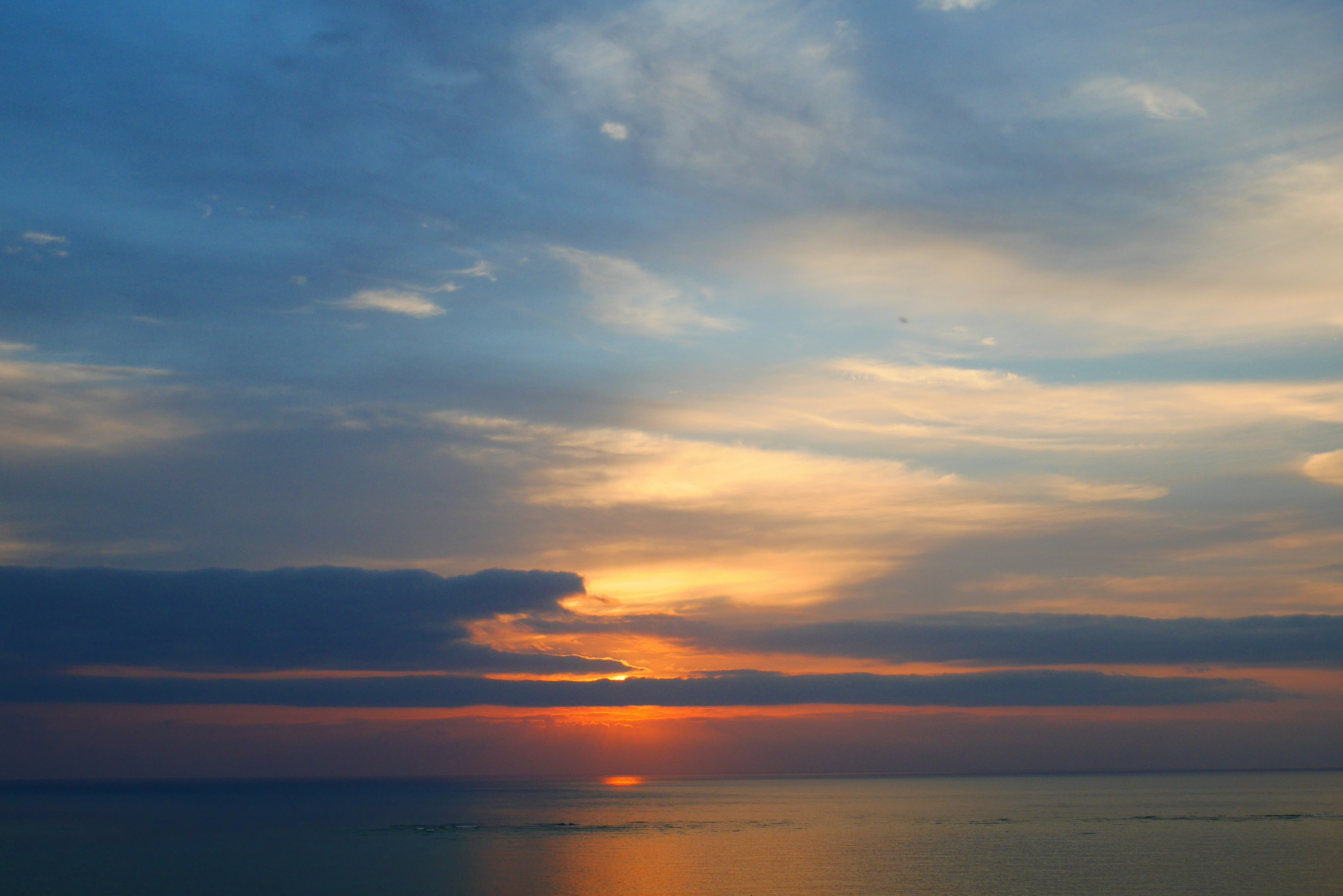 Atardecer dramático sobre el océano con nubes naranjas y moradas vibrantes