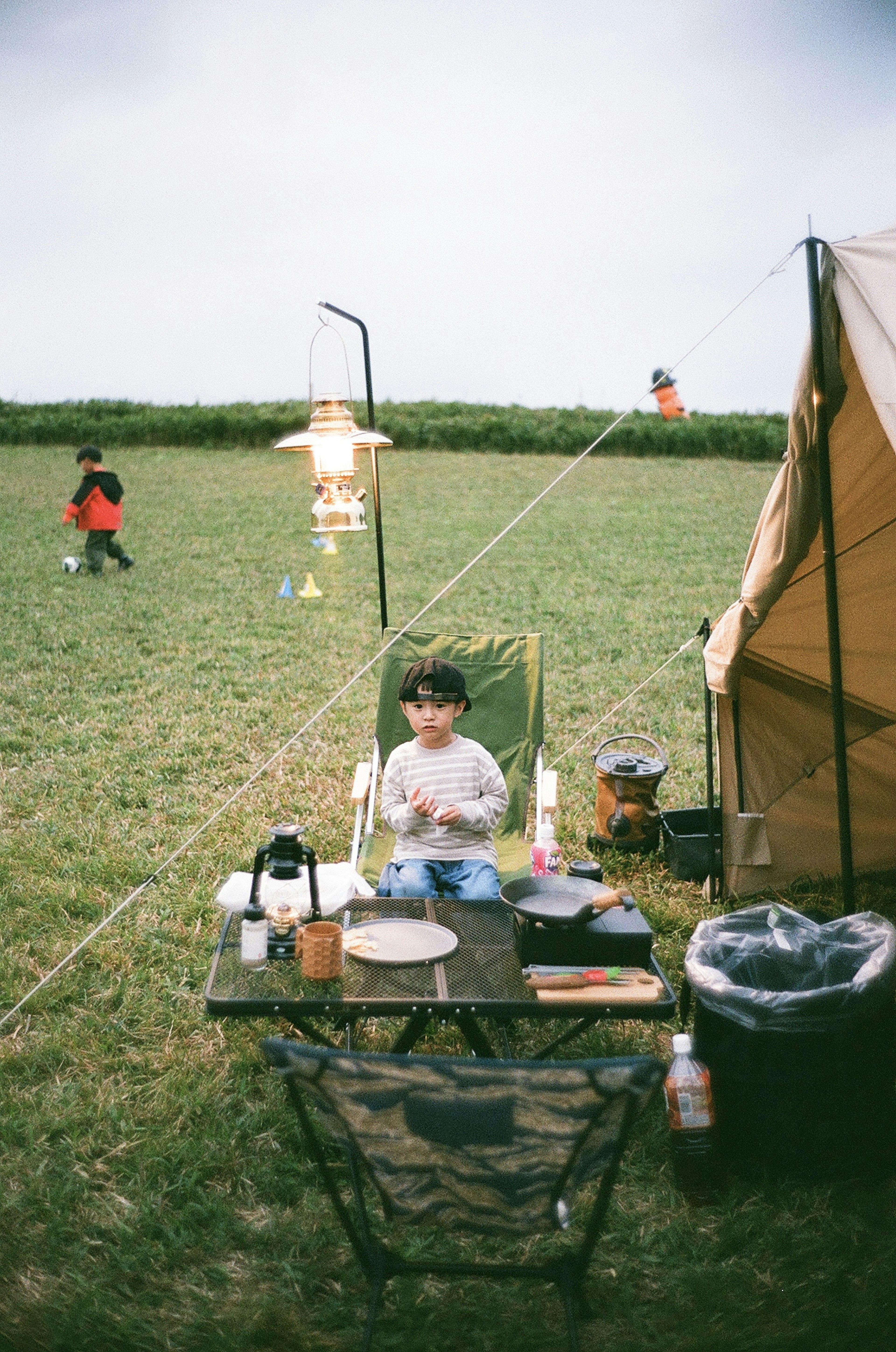 Ein Kind sitzt auf einem Campingstuhl und bereitet Essen in einem Campingplatz vor