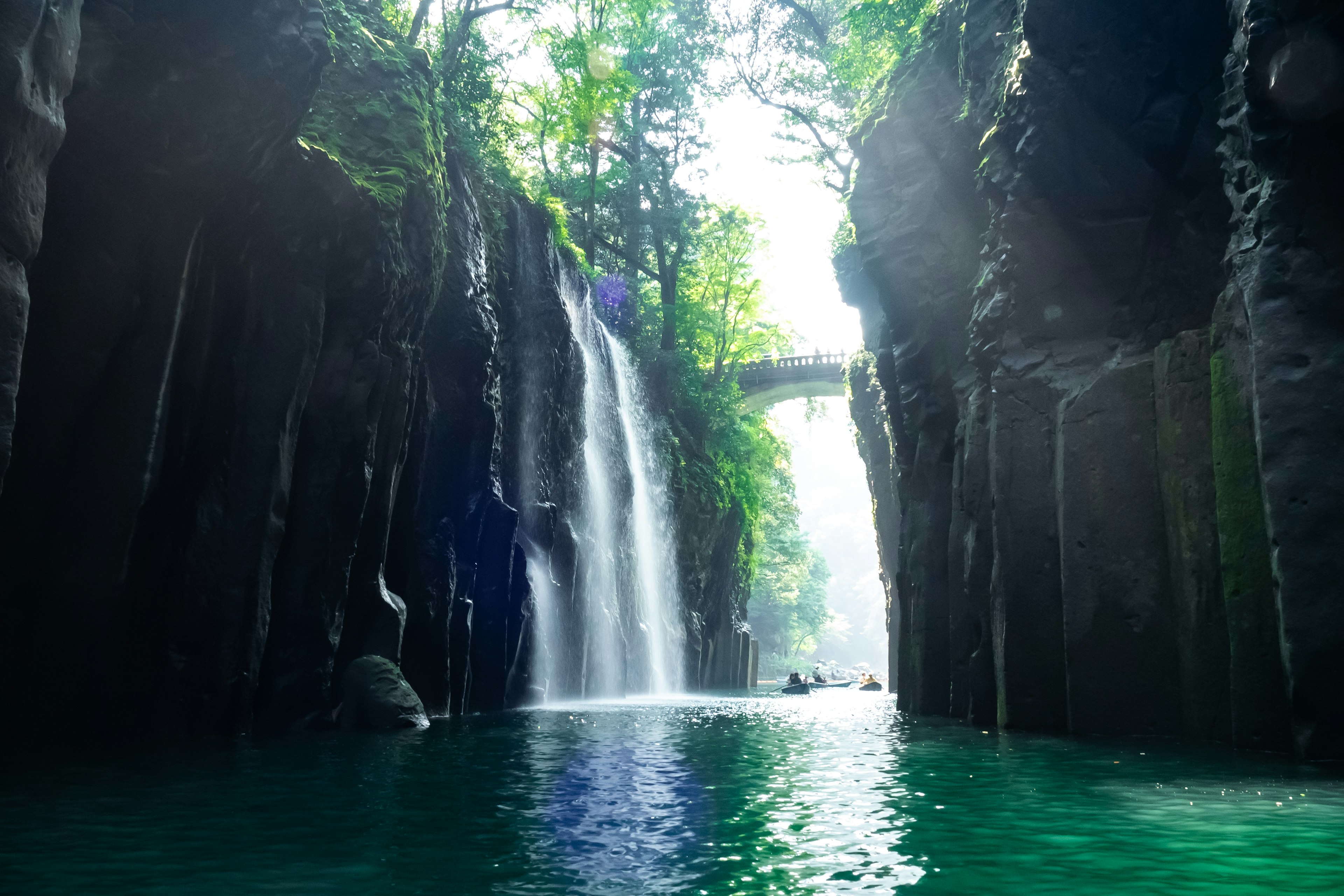 Eine ruhige Schlucht mit Wasserfällen, die von üppigen Klippen fallen