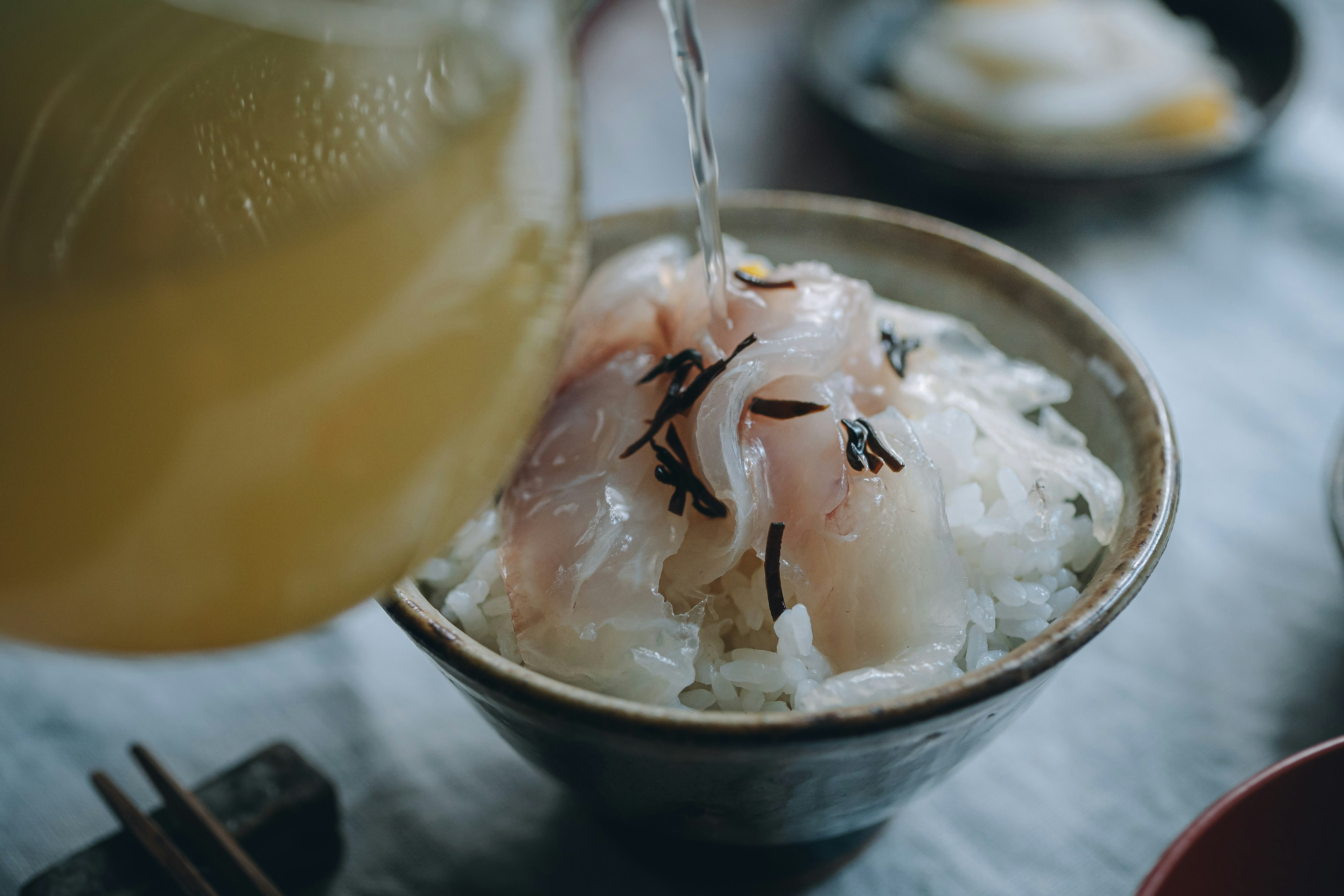 Un bol de riz surmonté de sashimi frais arrosé de bouillon