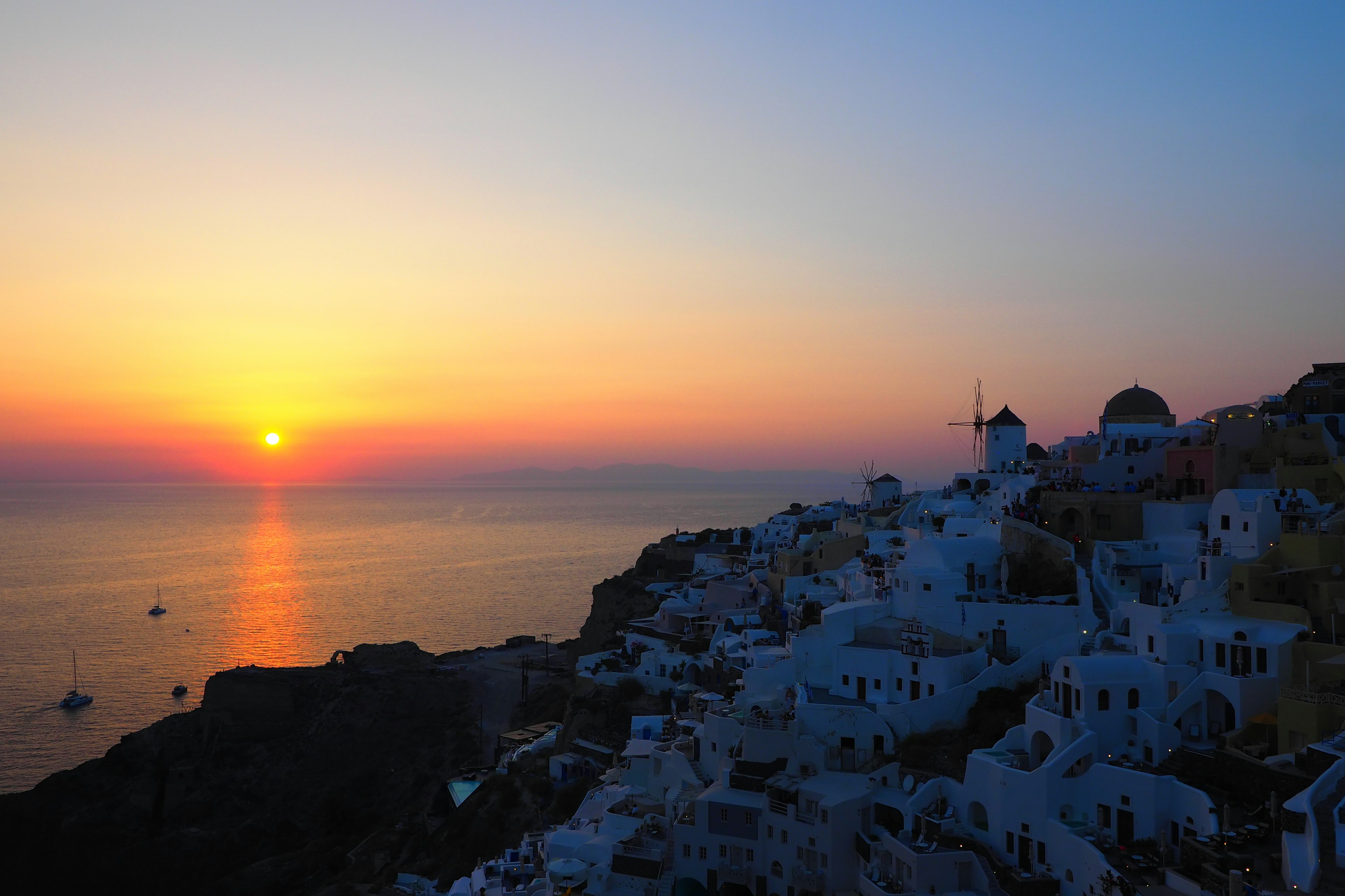 Magnifique coucher de soleil sur la mer à Santorin avec des bâtiments blancs et des dômes bleus