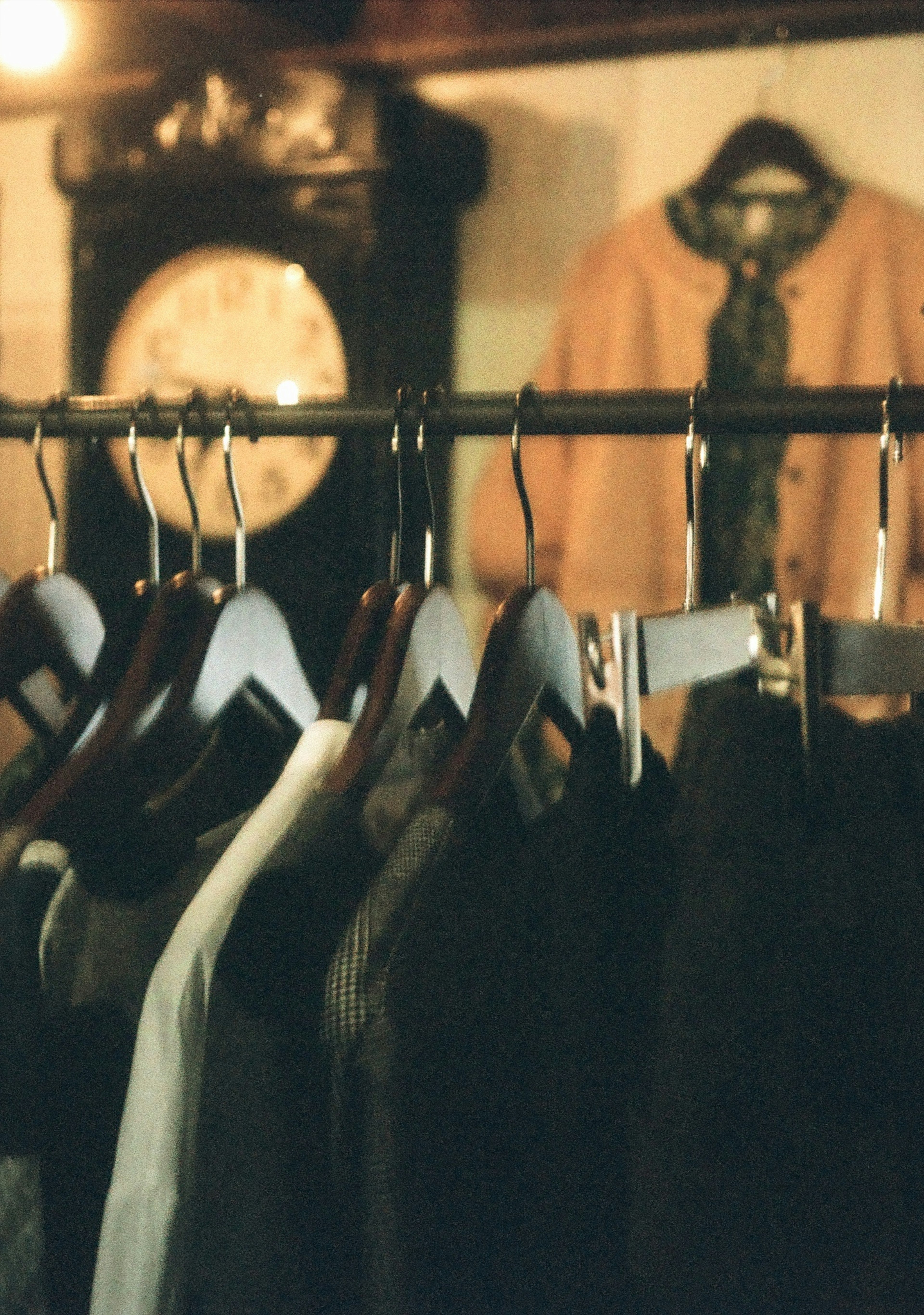 Clothes hanging on a rack with a vintage clock in the background