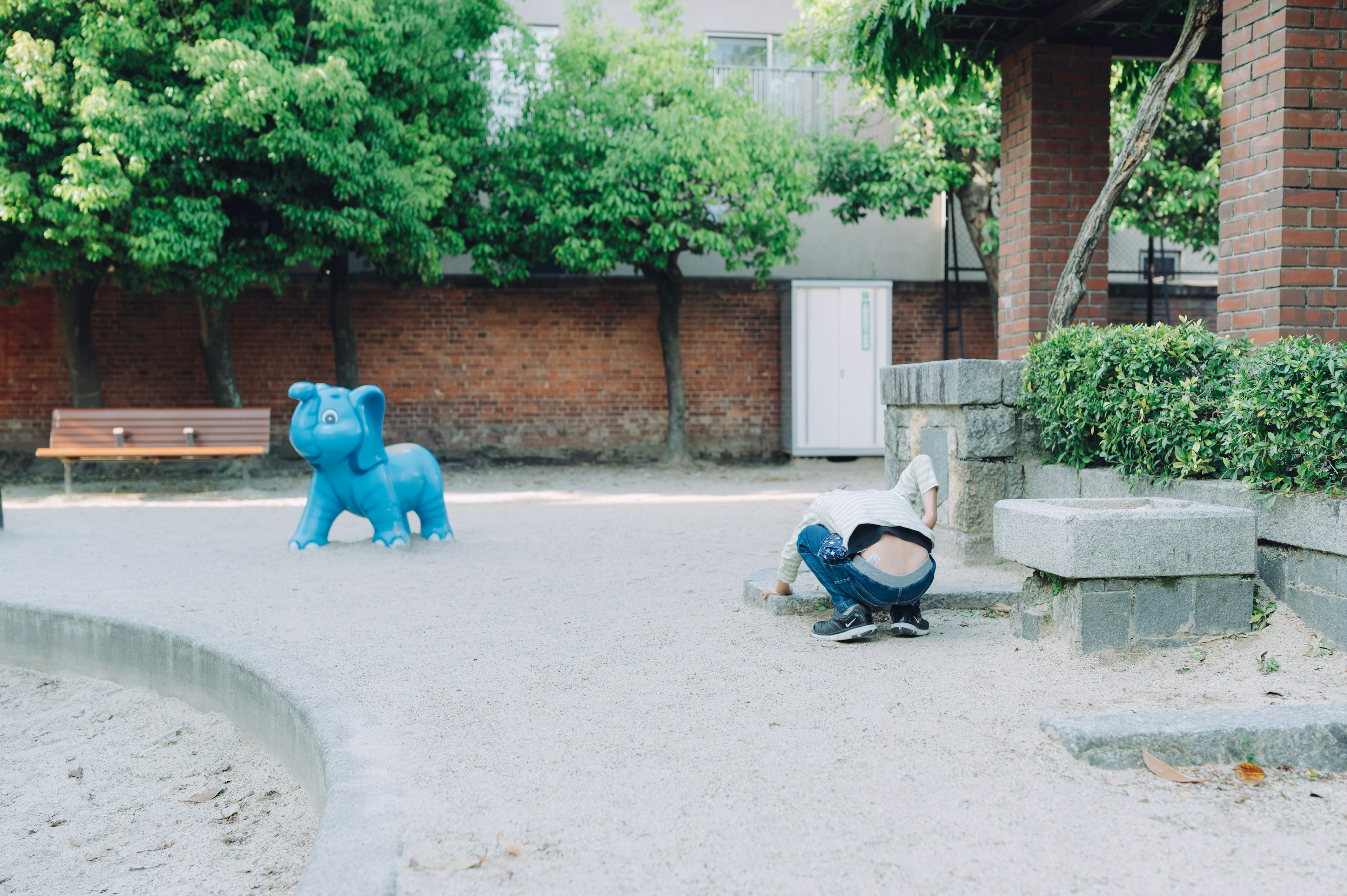 Una escultura de elefante azul en un parque con un niño jugando cerca