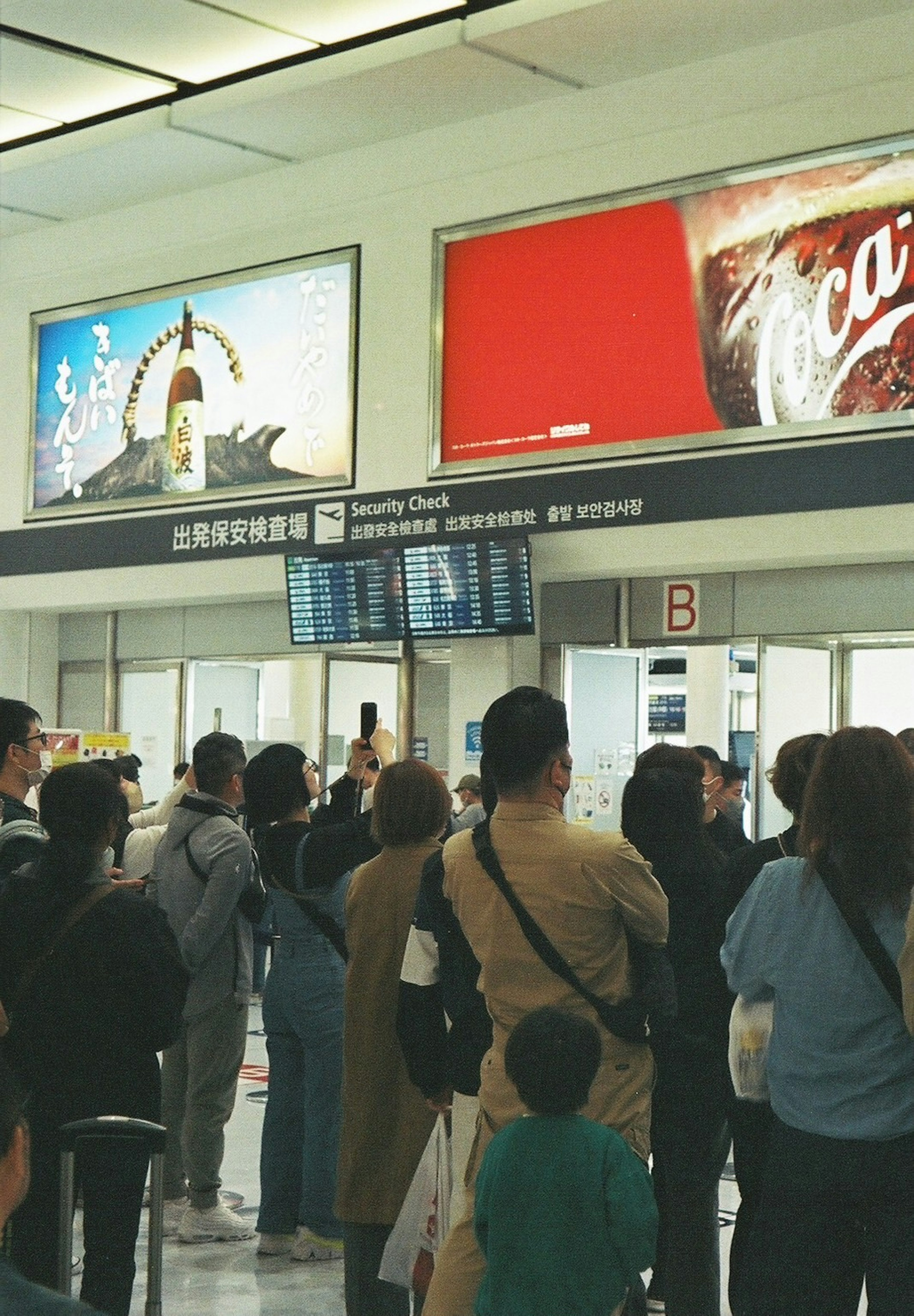 Orang-orang menunggu di meja check-in bandara dengan iklan