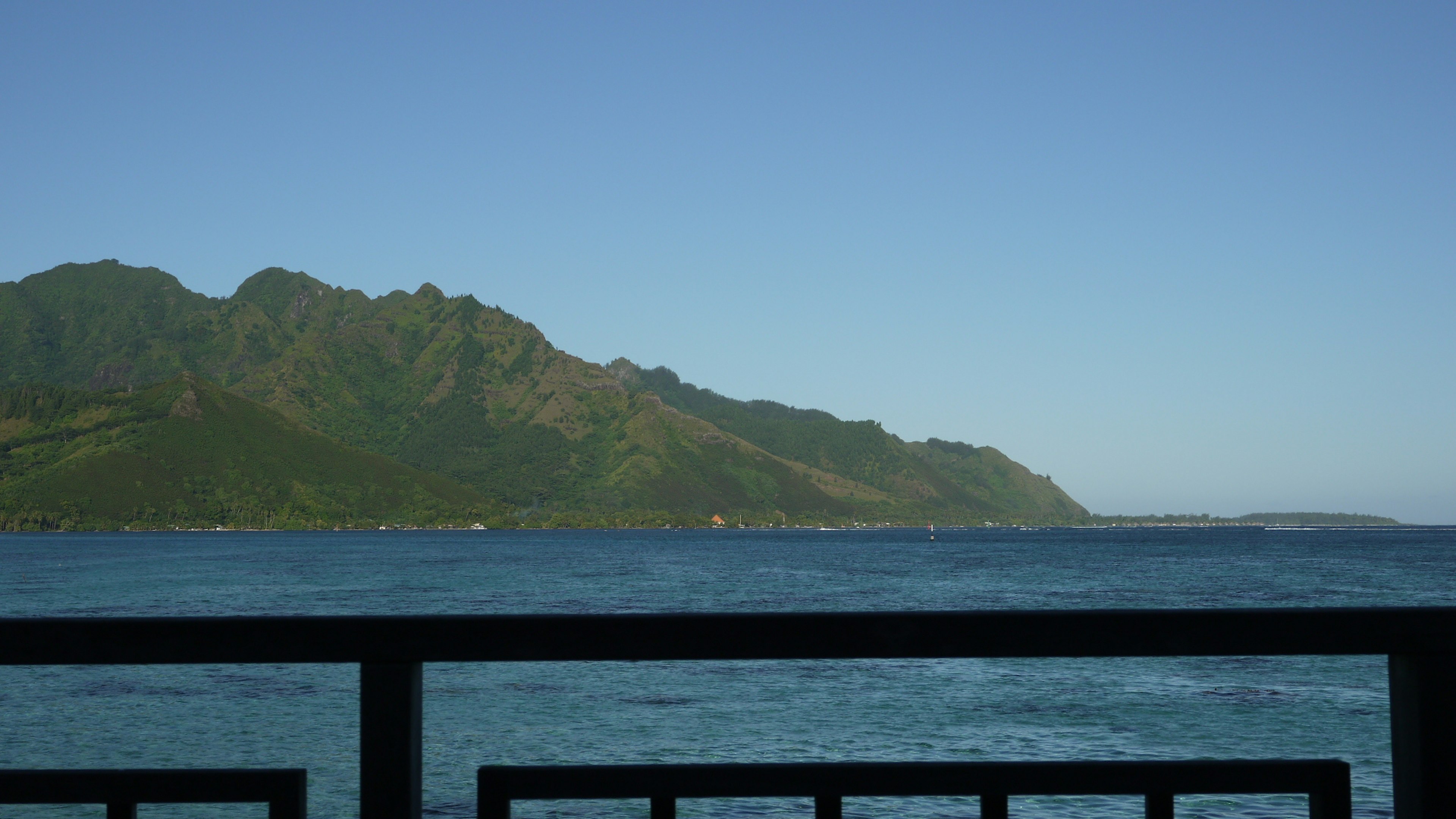 Scenic view of blue ocean with green mountains in the background