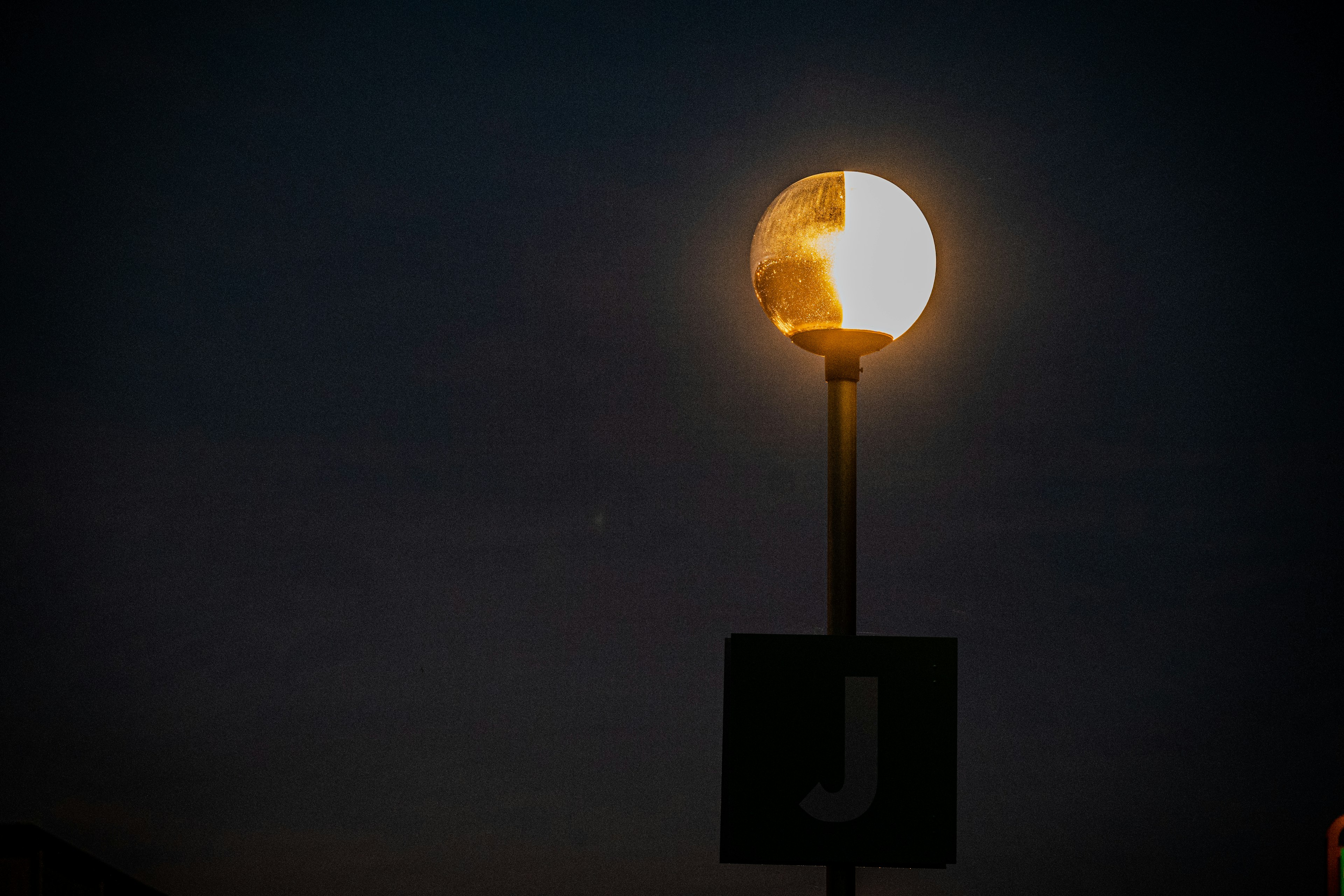 Lampadaire brillant dans le ciel nocturne avec un panneau J