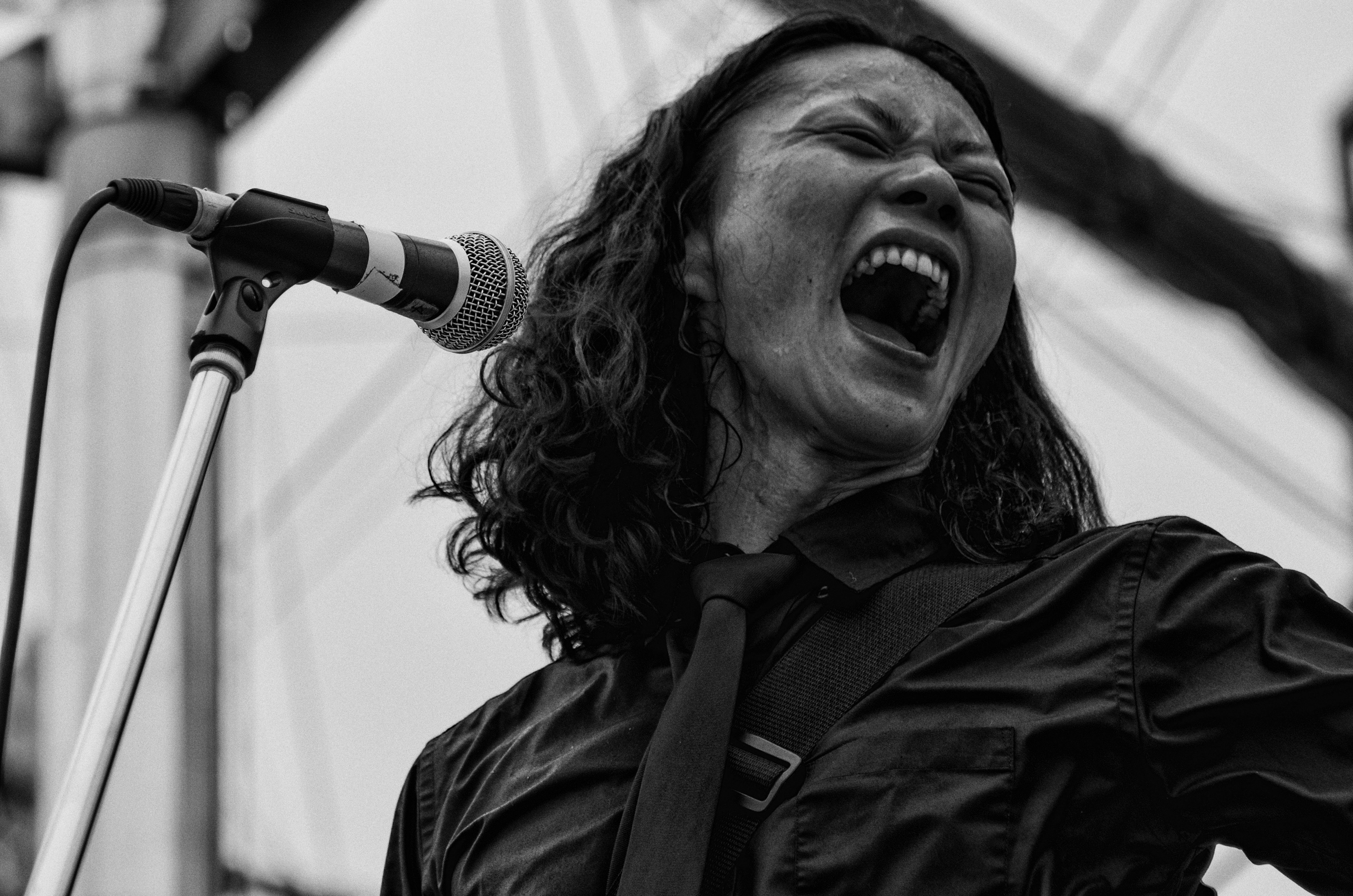 A black and white image of a woman passionately singing into a microphone