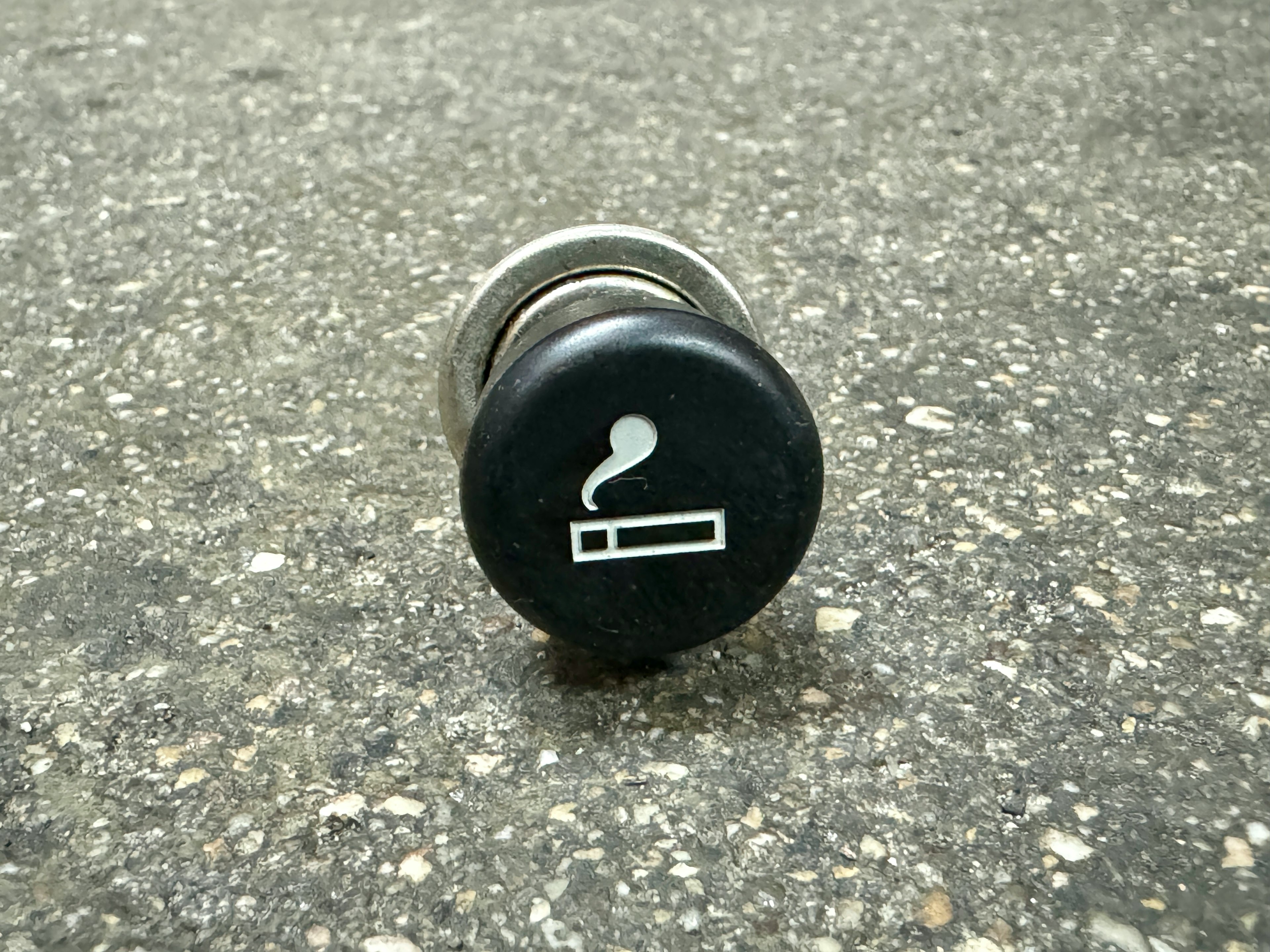 A black cigarette lighter socket on a textured surface