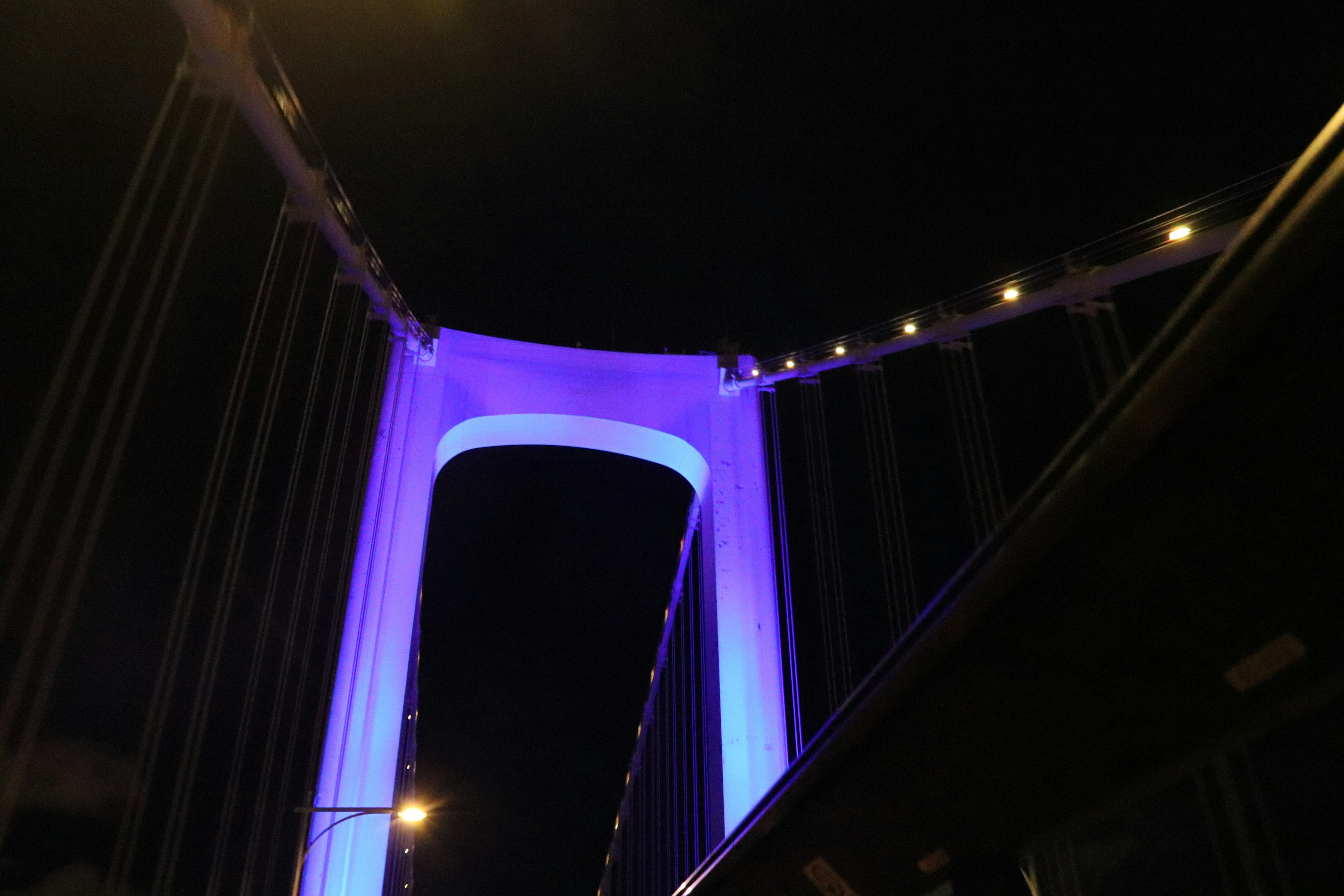 Bogen einer Brücke, der nachts lila beleuchtet ist