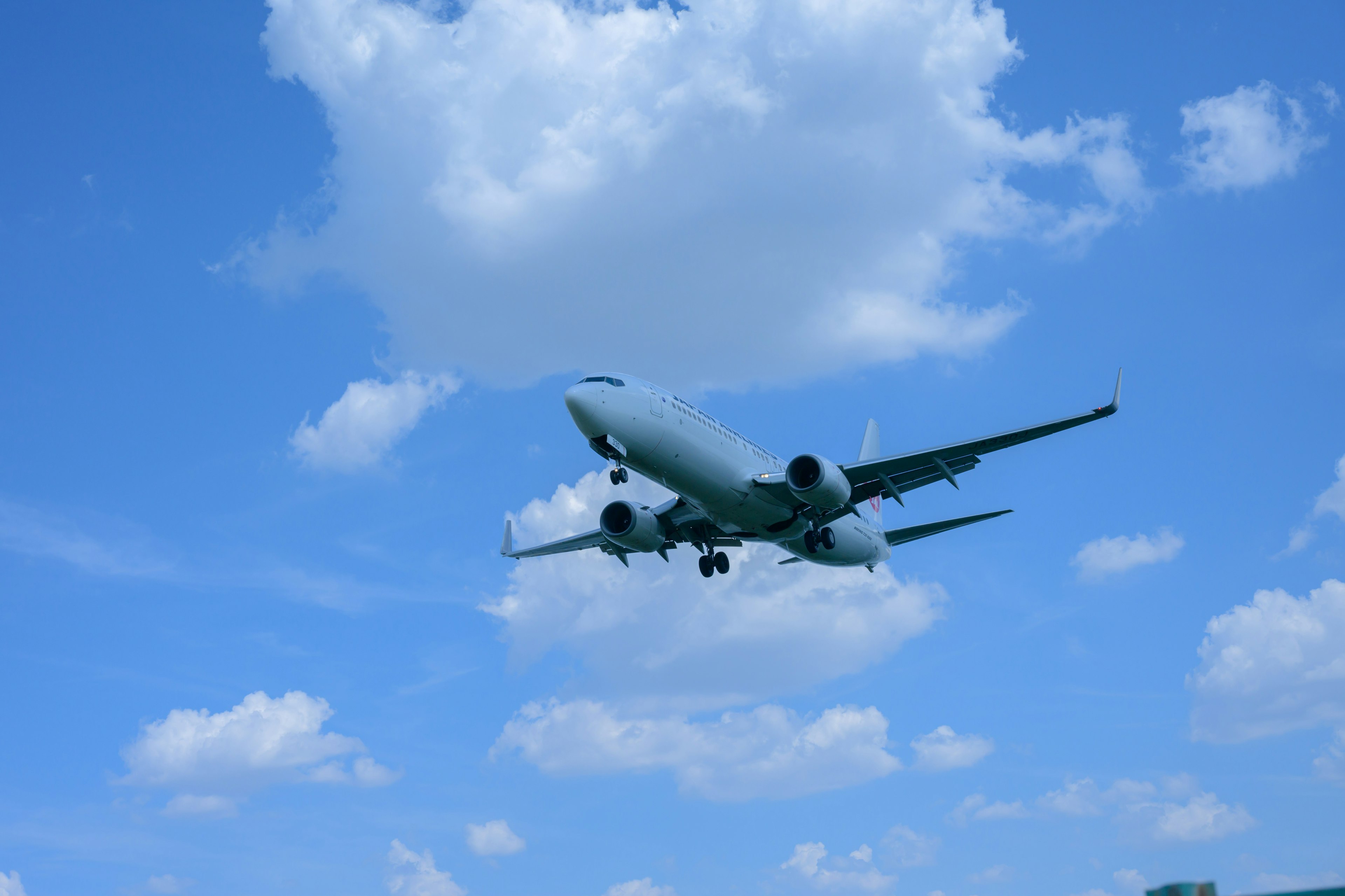 青空の中を飛行する旅客機と白い雲