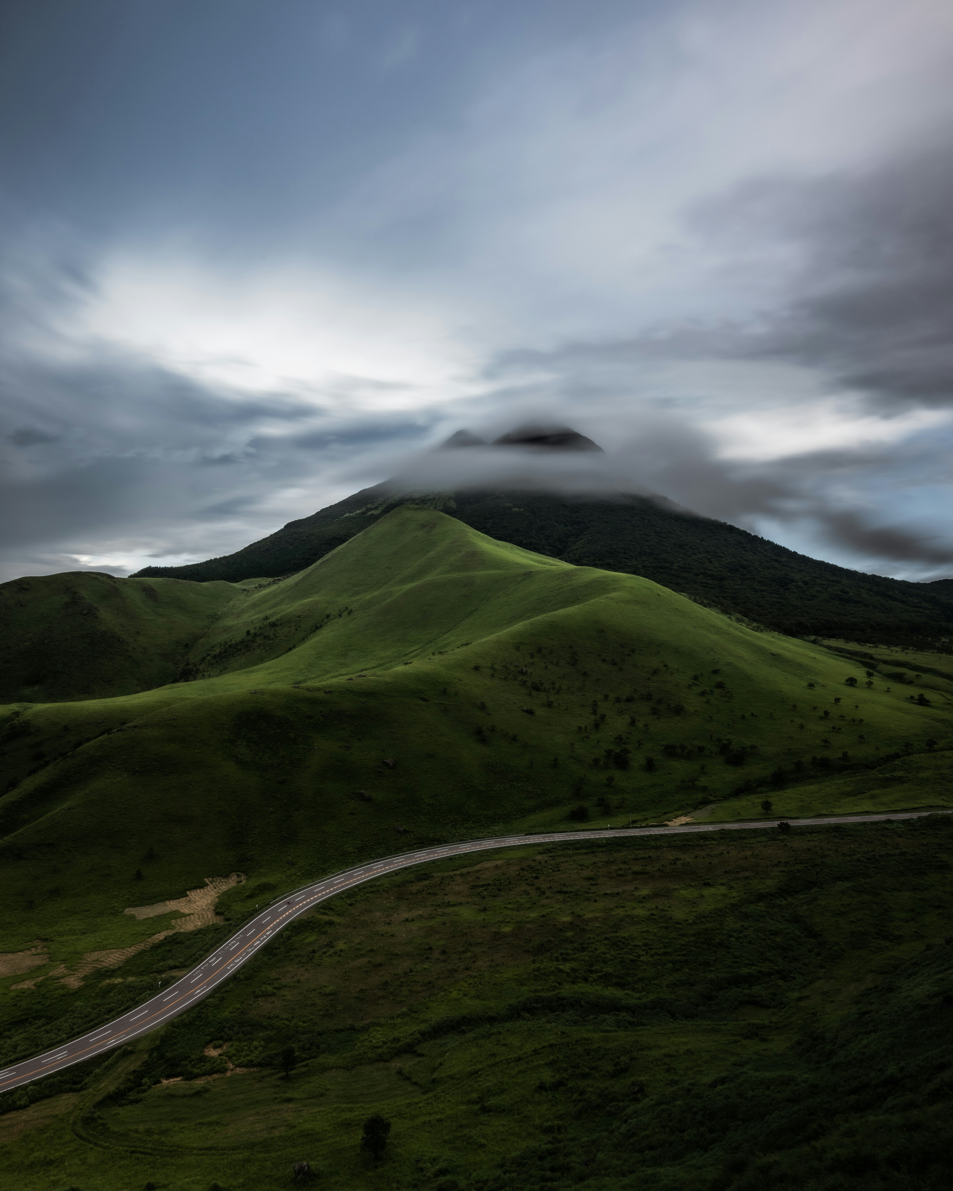 緑の丘と雲に覆われた山の風景