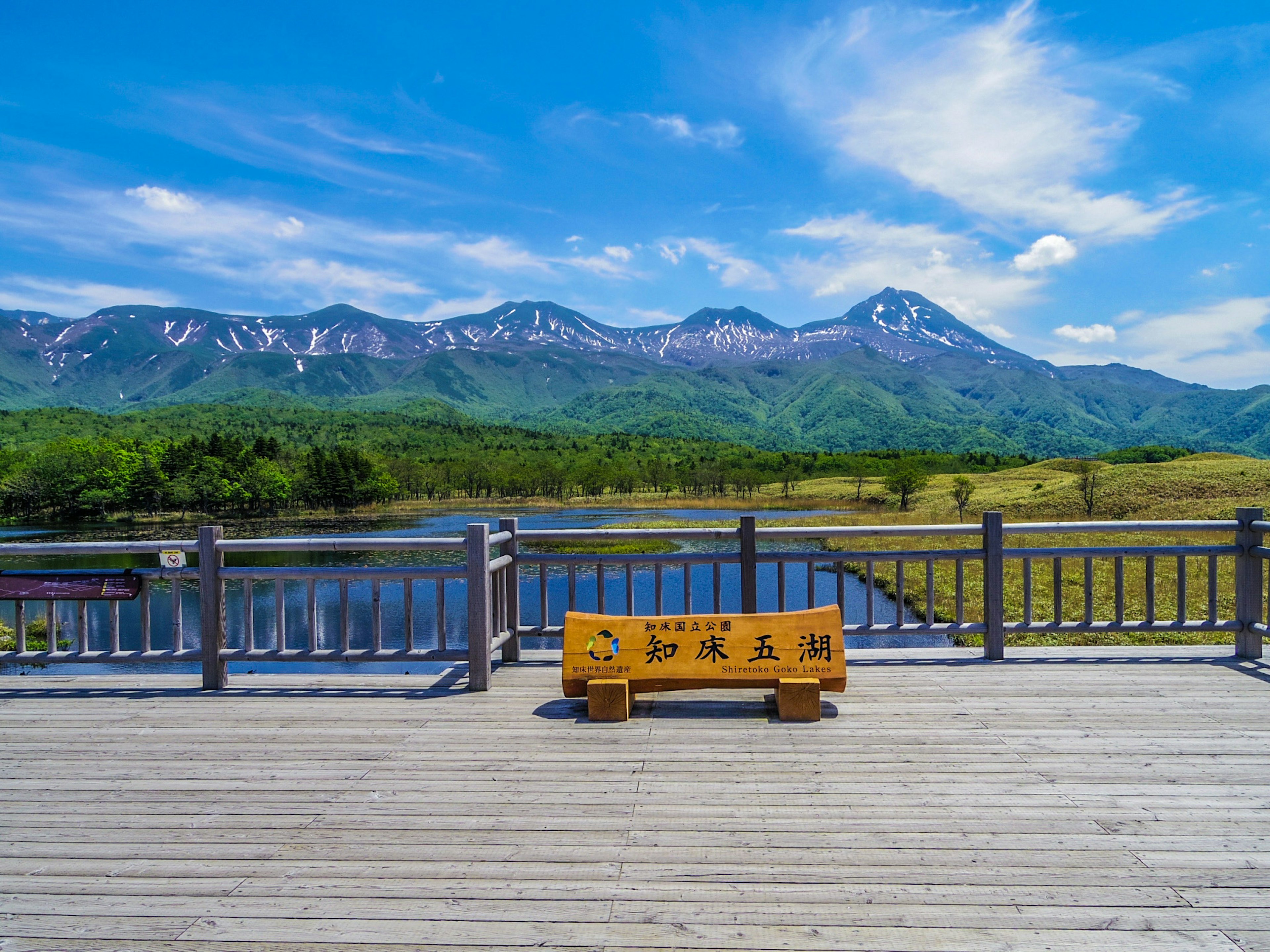 美麗的山脈和藍天的風景，甲板上有一張木製長椅