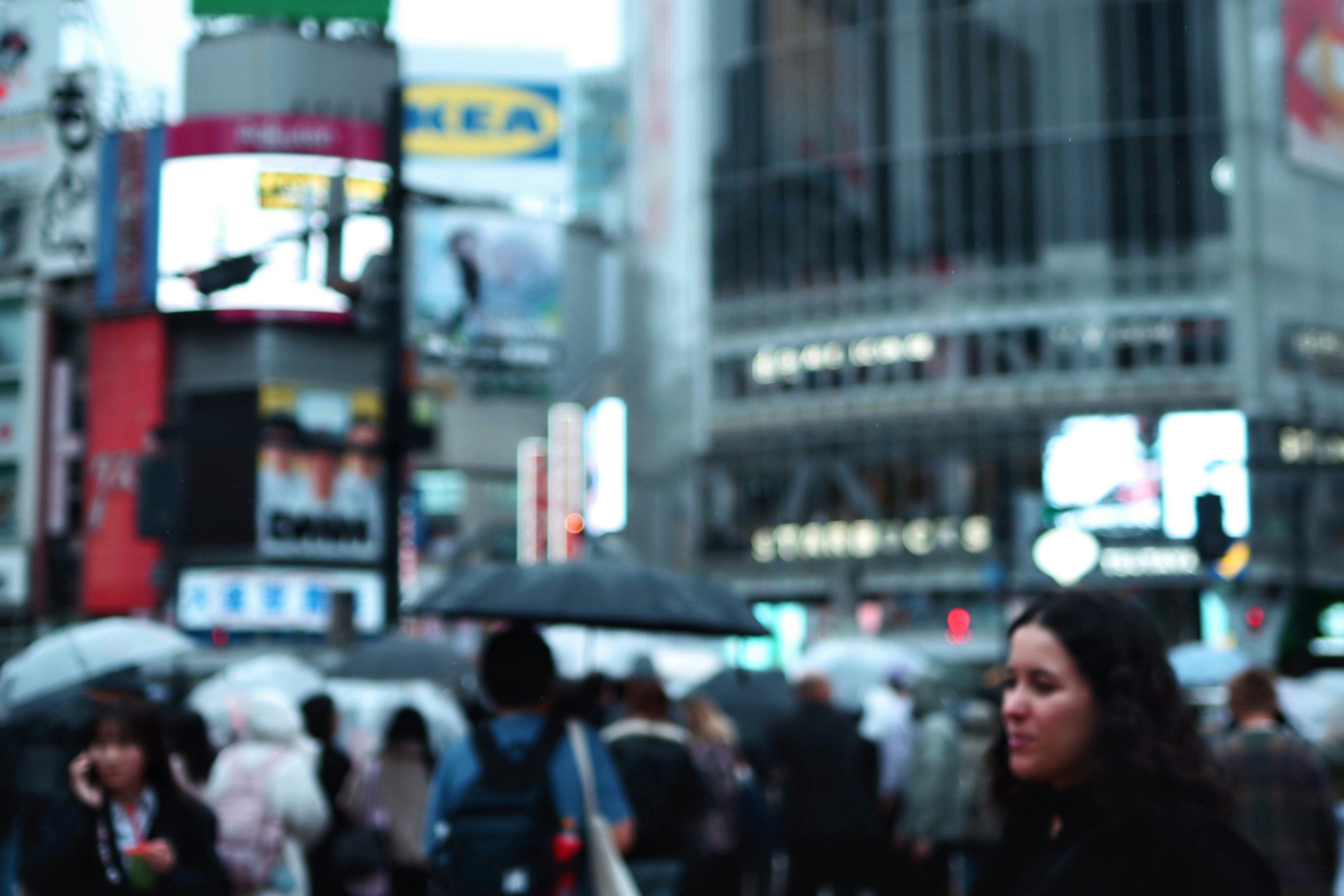 Folla di persone con ombrelli nel quartiere commerciale di Shibuya