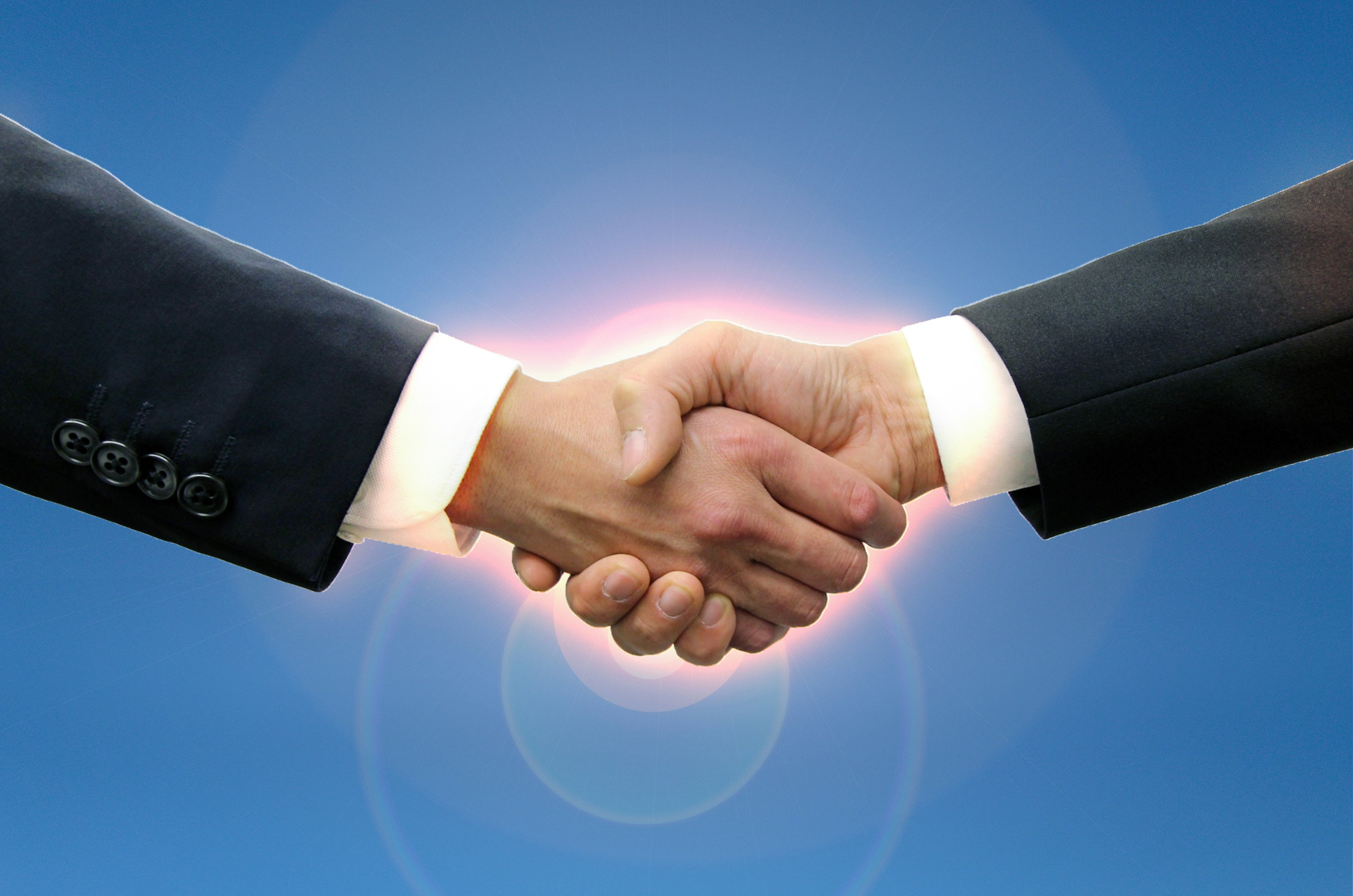 Image showing a handshake between two businessmen with a blue sky background