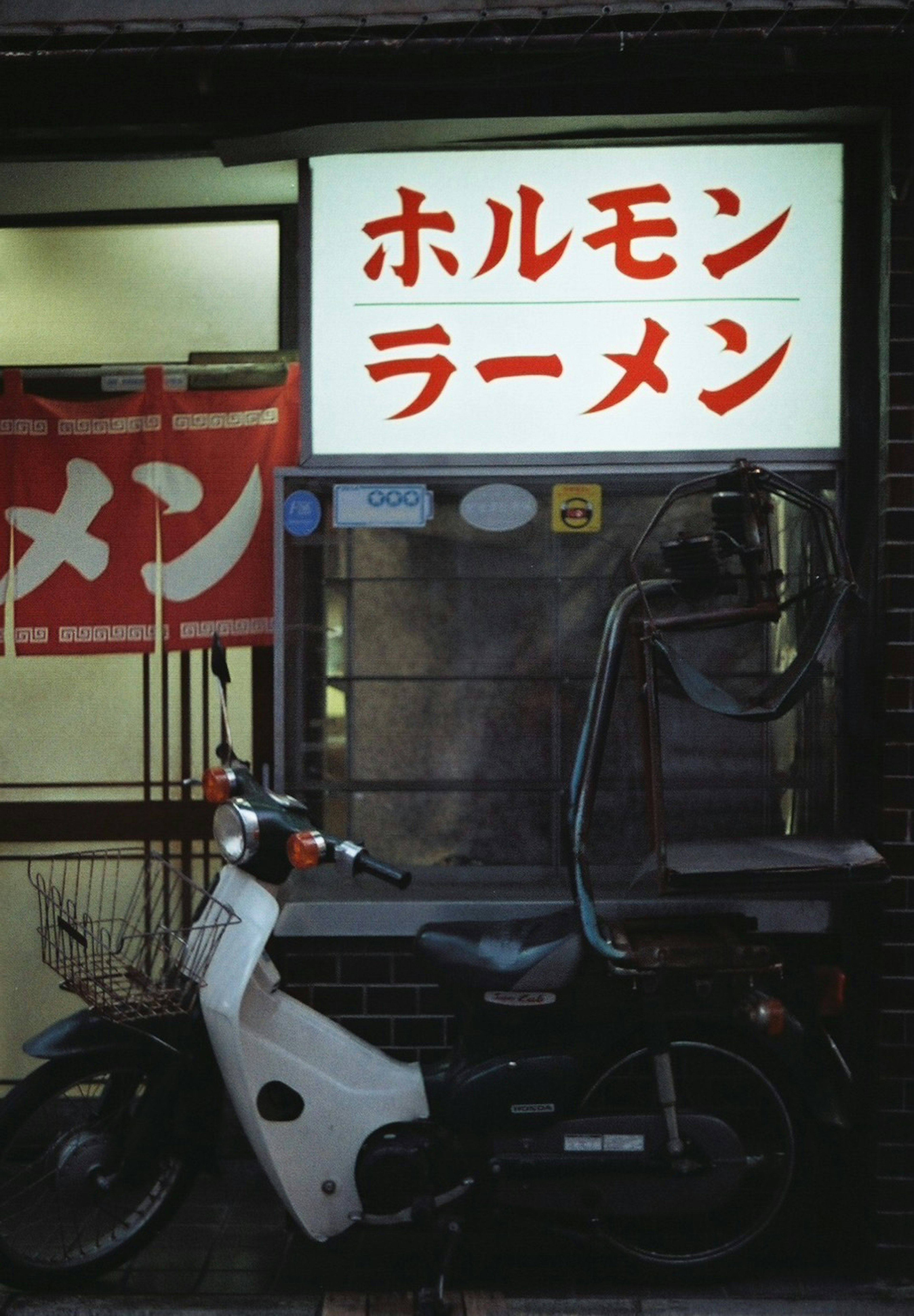 ホルモンラーメンの看板がある店舗の外観と白いバイク