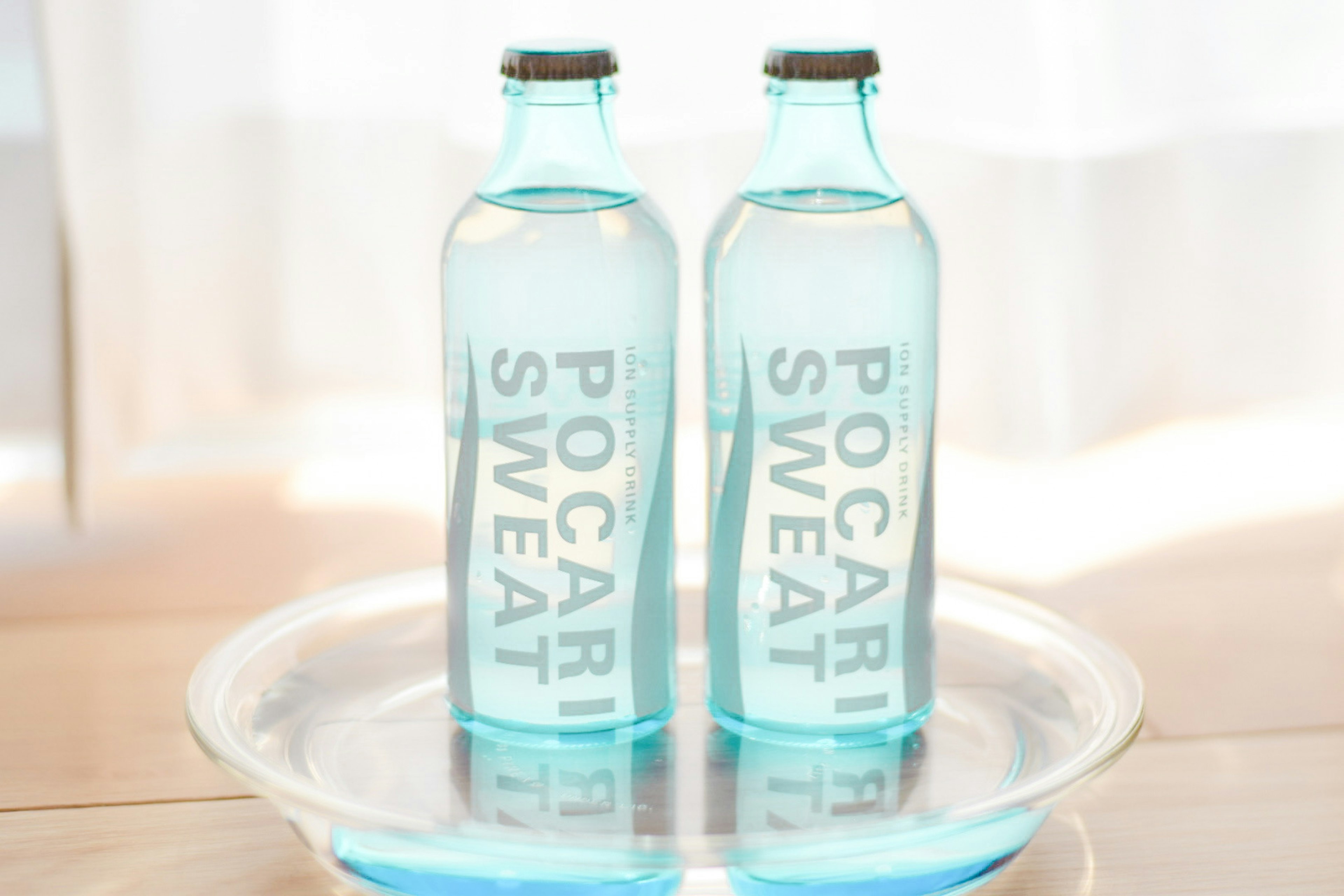 Two transparent bottles of Pocari Sweat on a glass plate