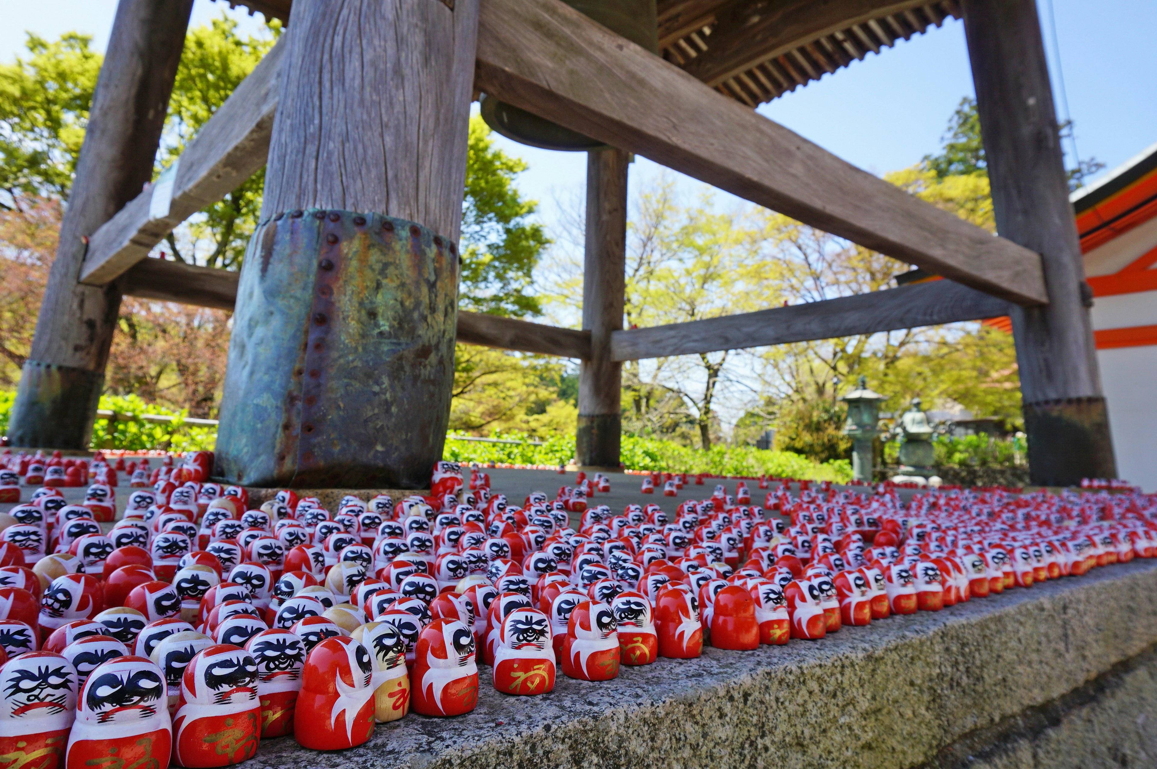 A scene under a bell with numerous red daruma dolls arranged neatly