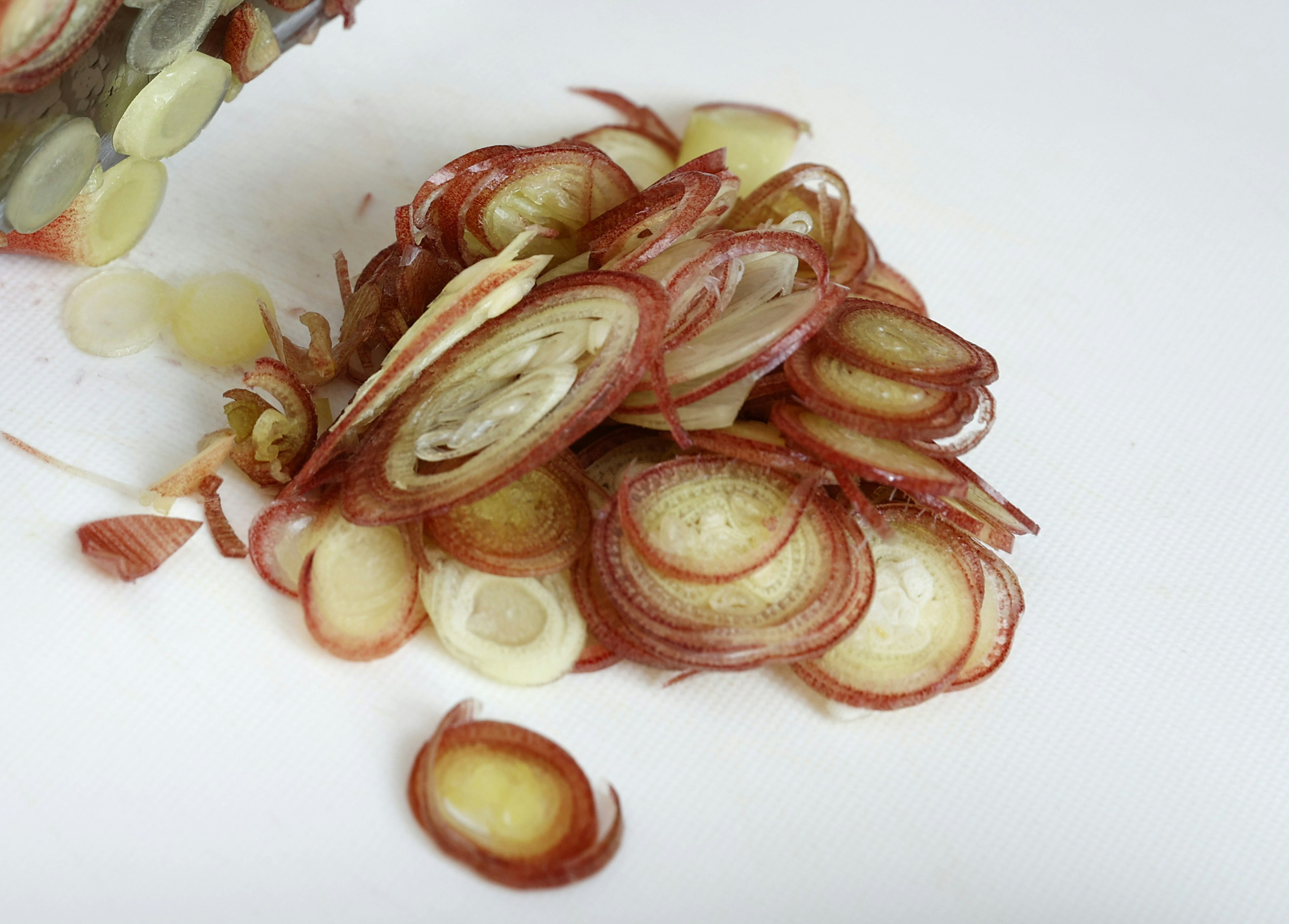 Rodajas de cebolla roja esparcidas sobre un fondo blanco