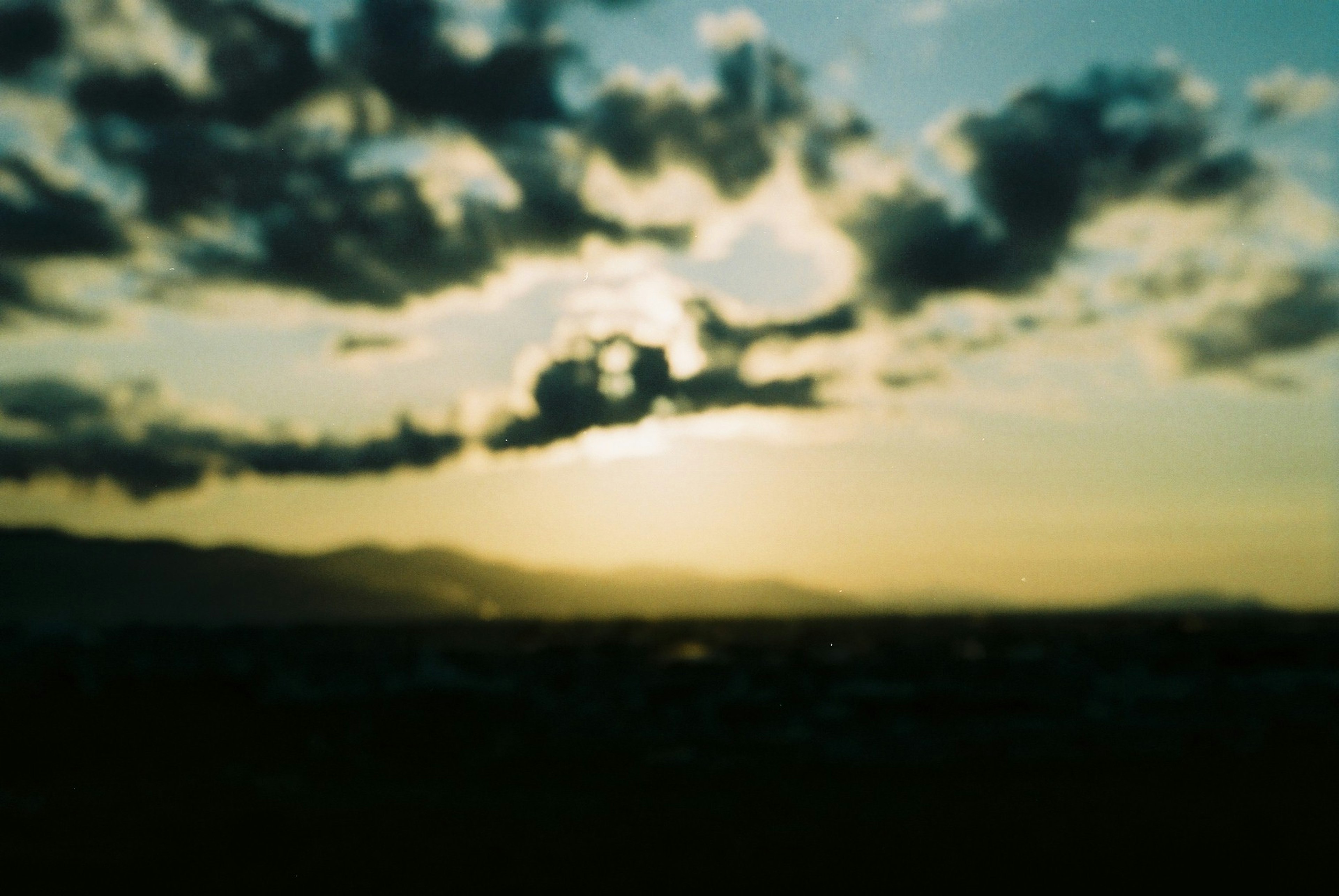 Verschommener Sonnenuntergang mit Wolken und Bergen