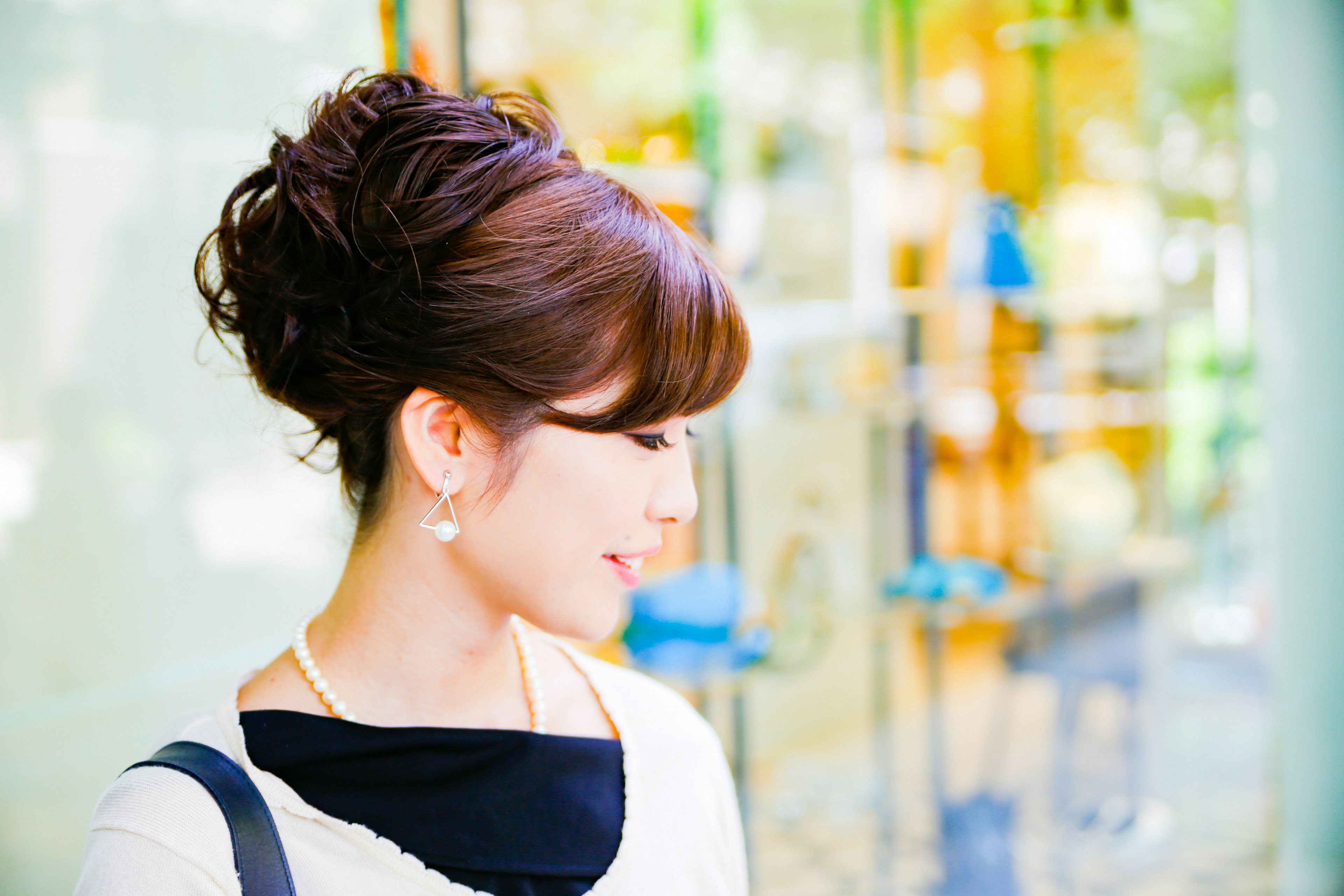 Une femme avec une coiffure élégante souriant en regardant sur le côté avec un fond de magasin coloré