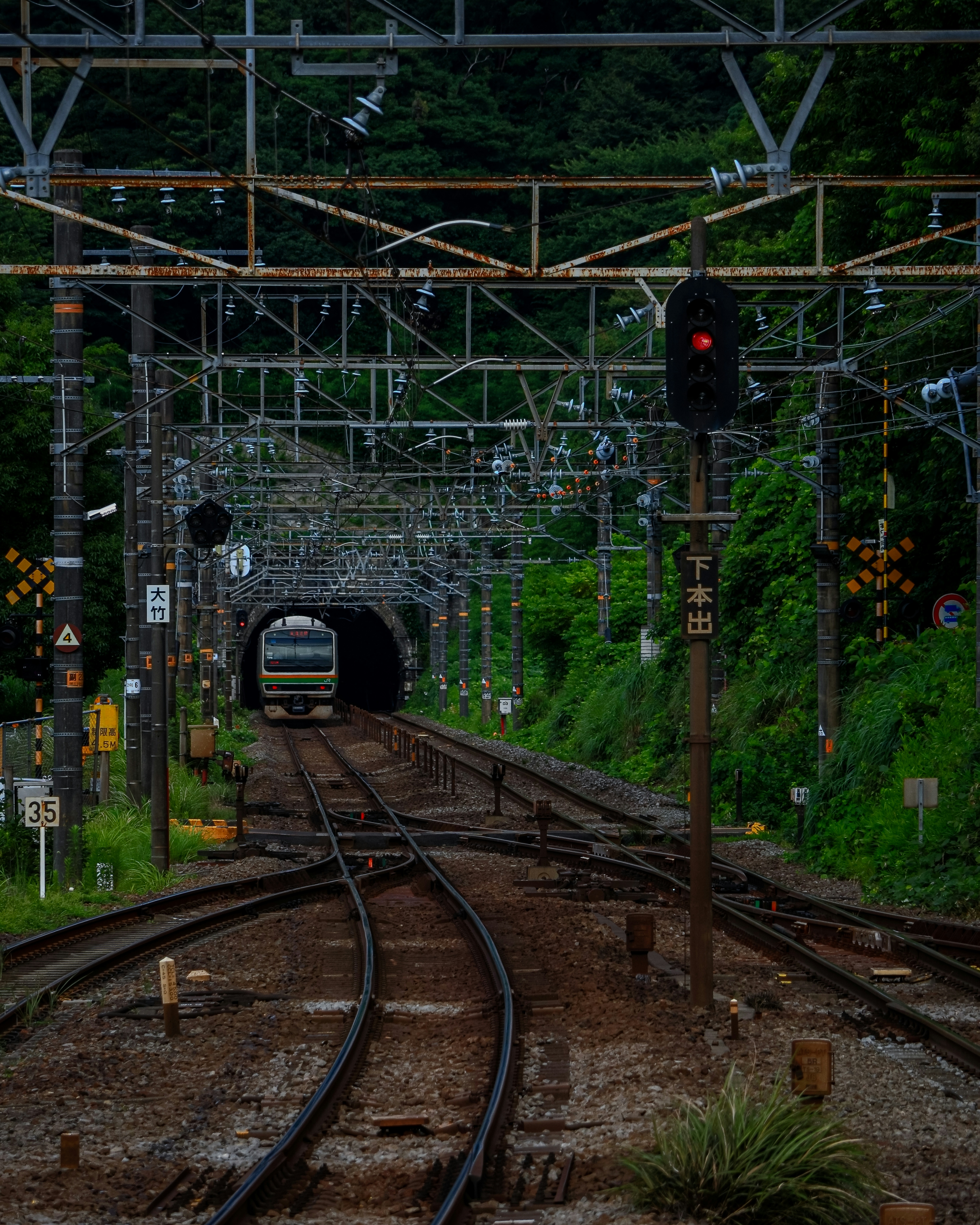 鉄道のトンネルに向かう列車の画像 線路と信号機が見える