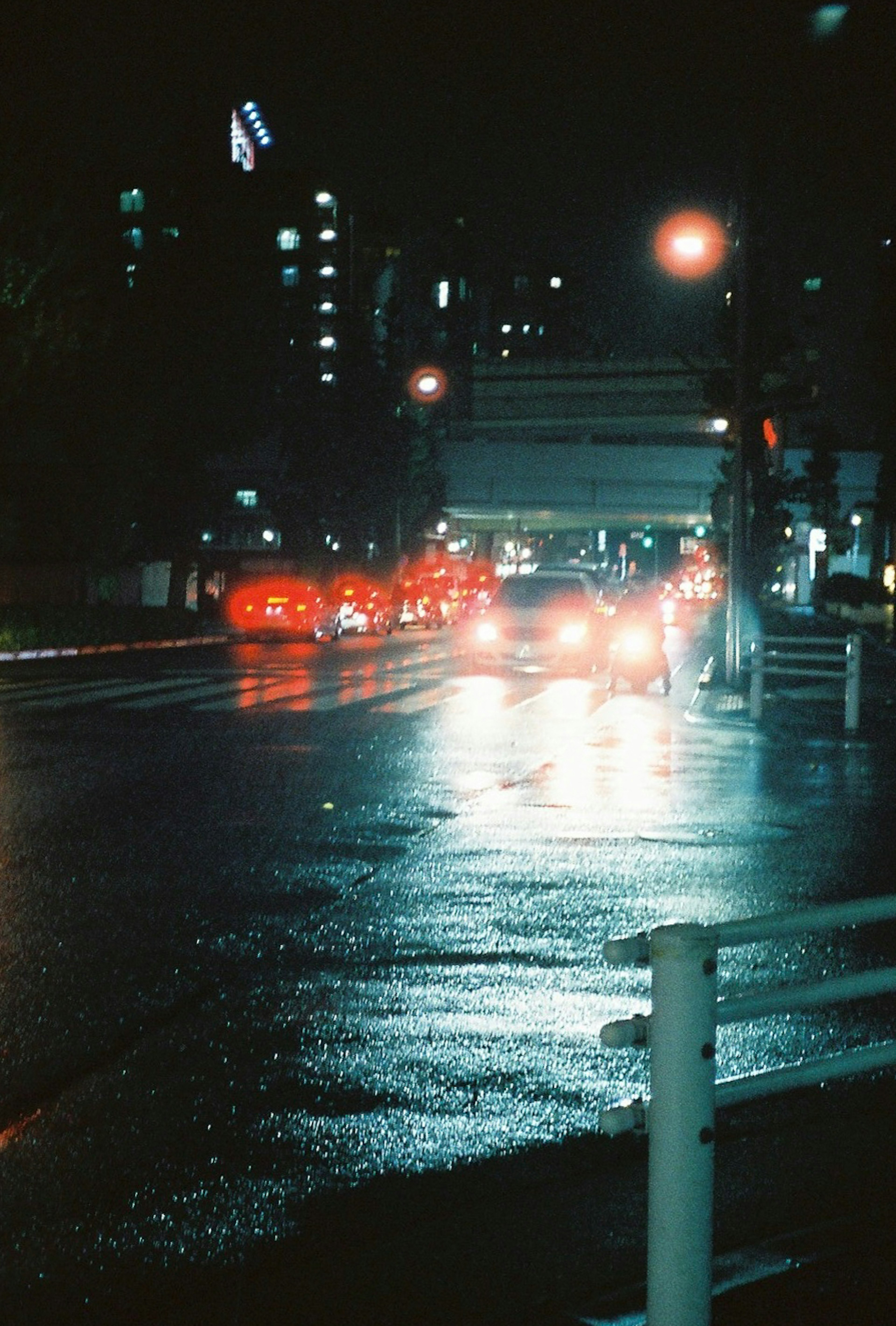 Wet street at night with car headlights and city lights