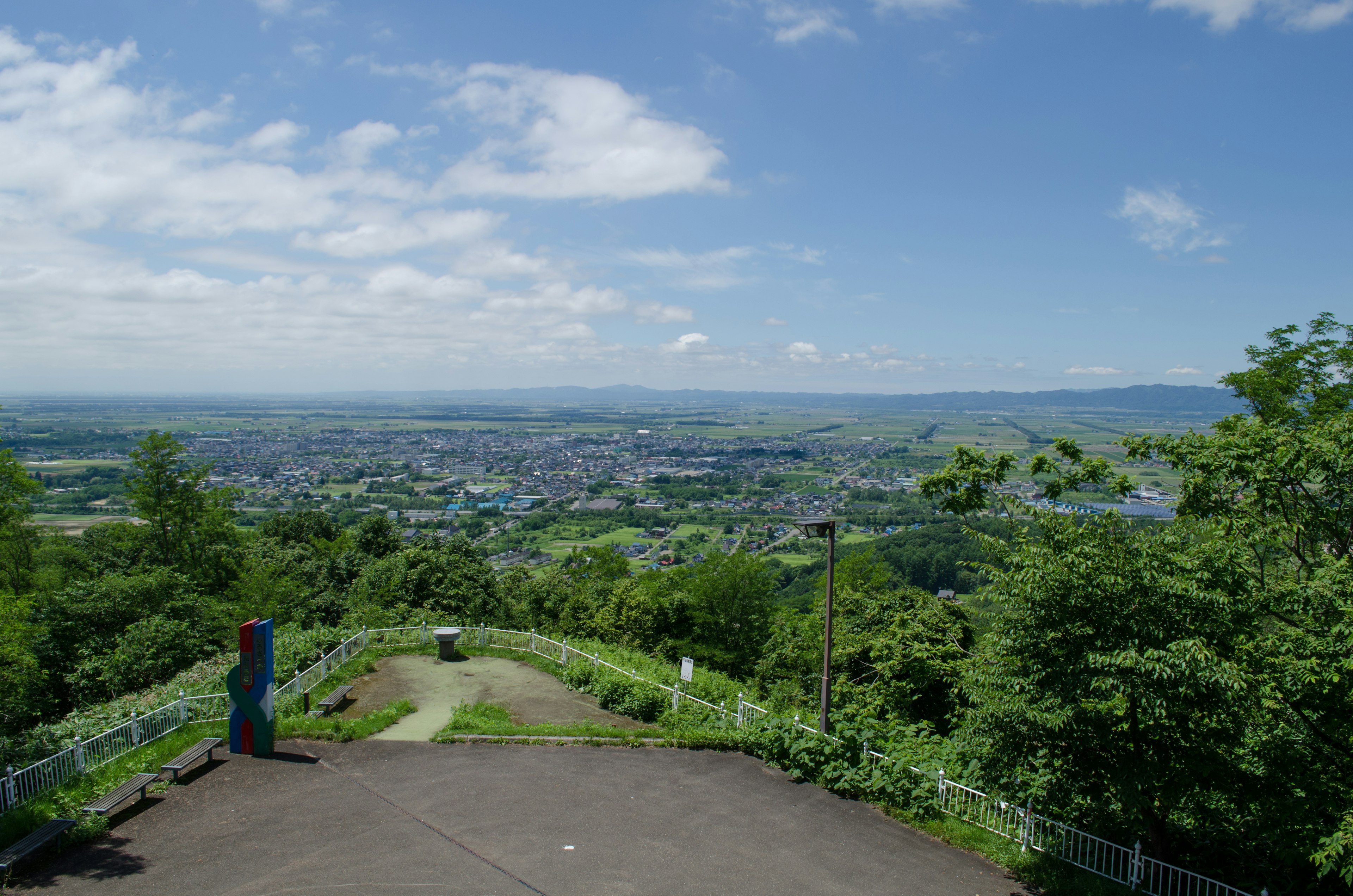 Vue panoramique depuis un point de vue en montagne entouré de verdure sous un ciel bleu