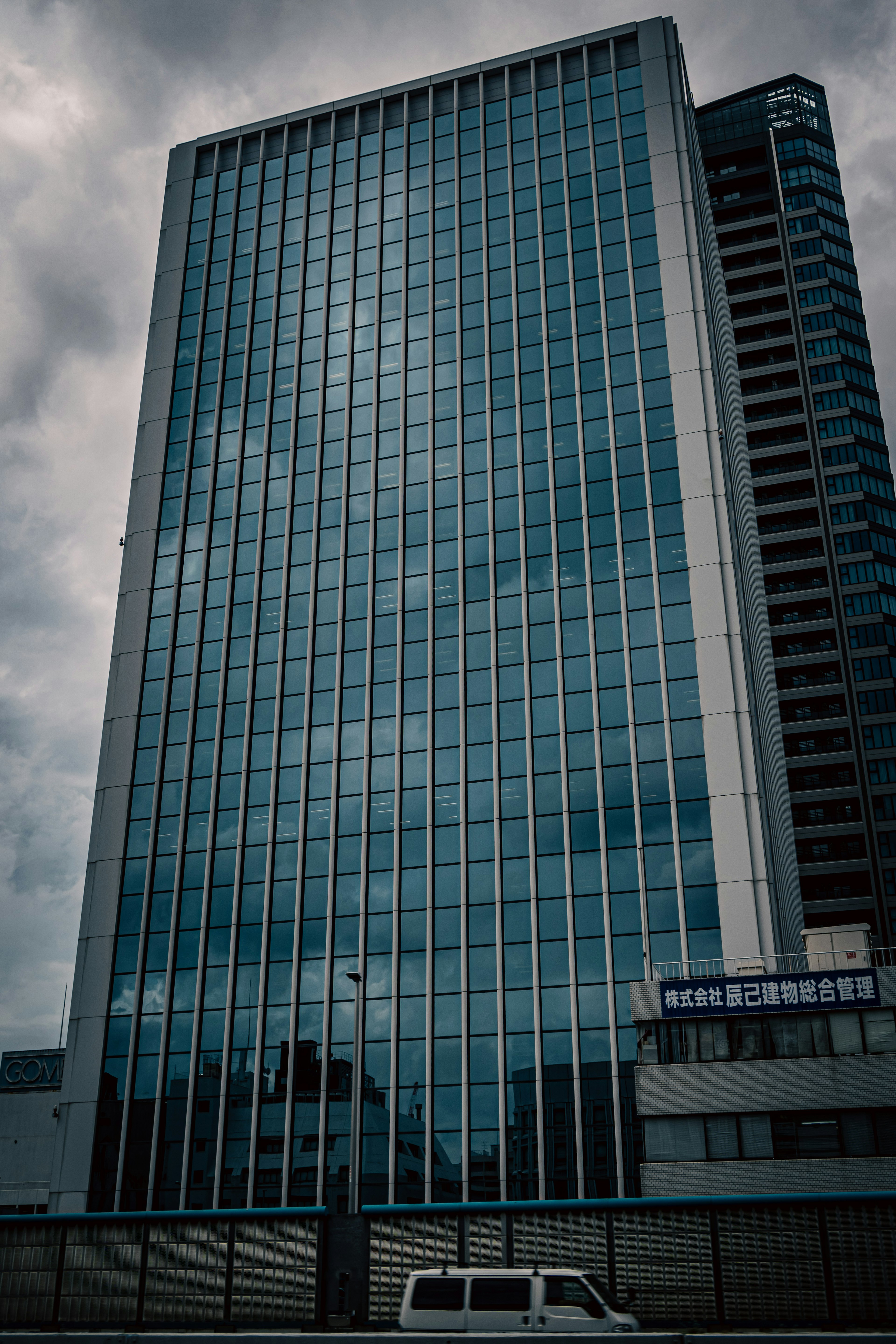 Edificio alto con facciata in vetro che riflette un cielo nuvoloso