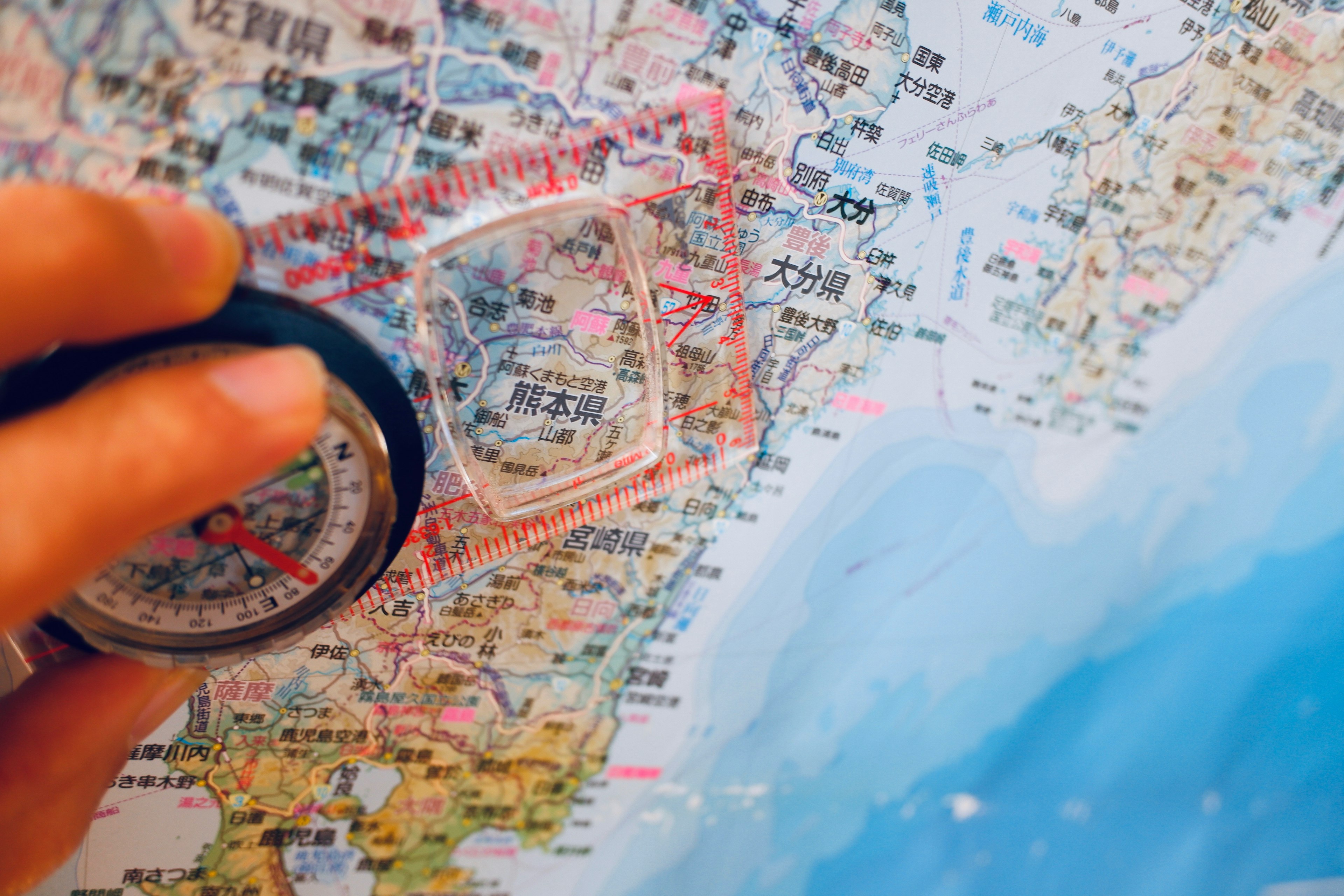 A hand holding a compass over a detailed map