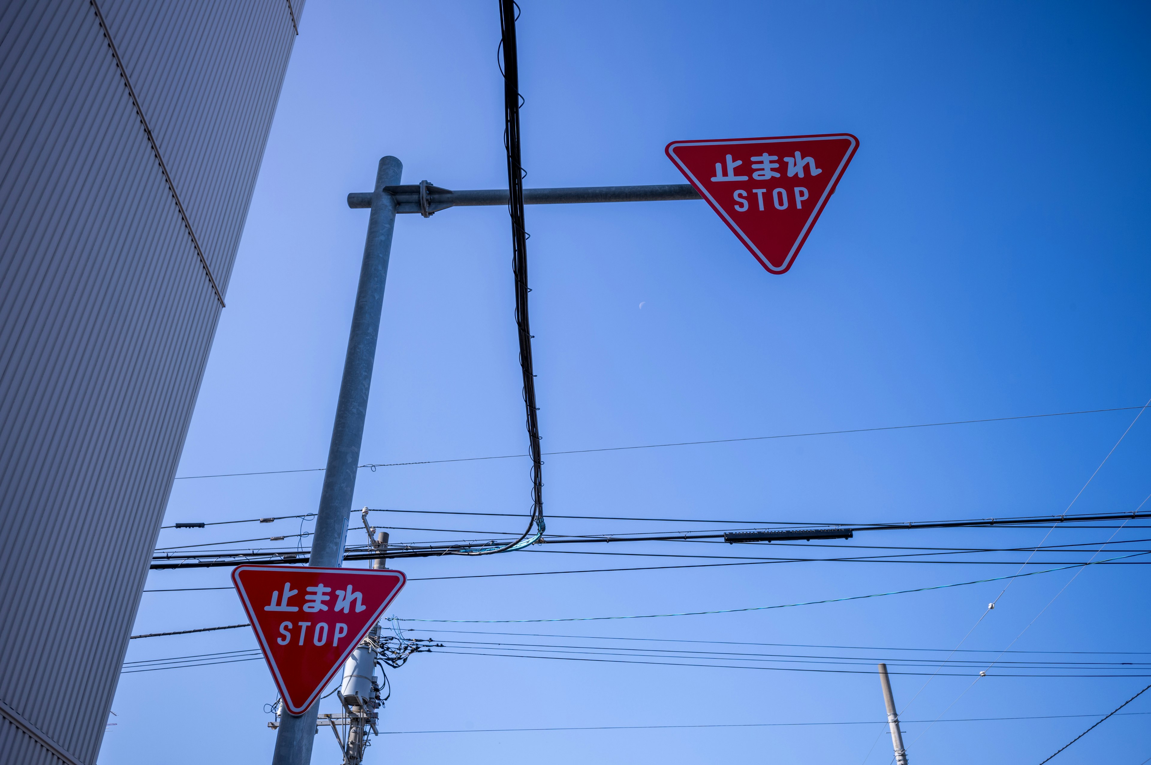 Deux panneaux stop triangulaires rouges sous un ciel bleu