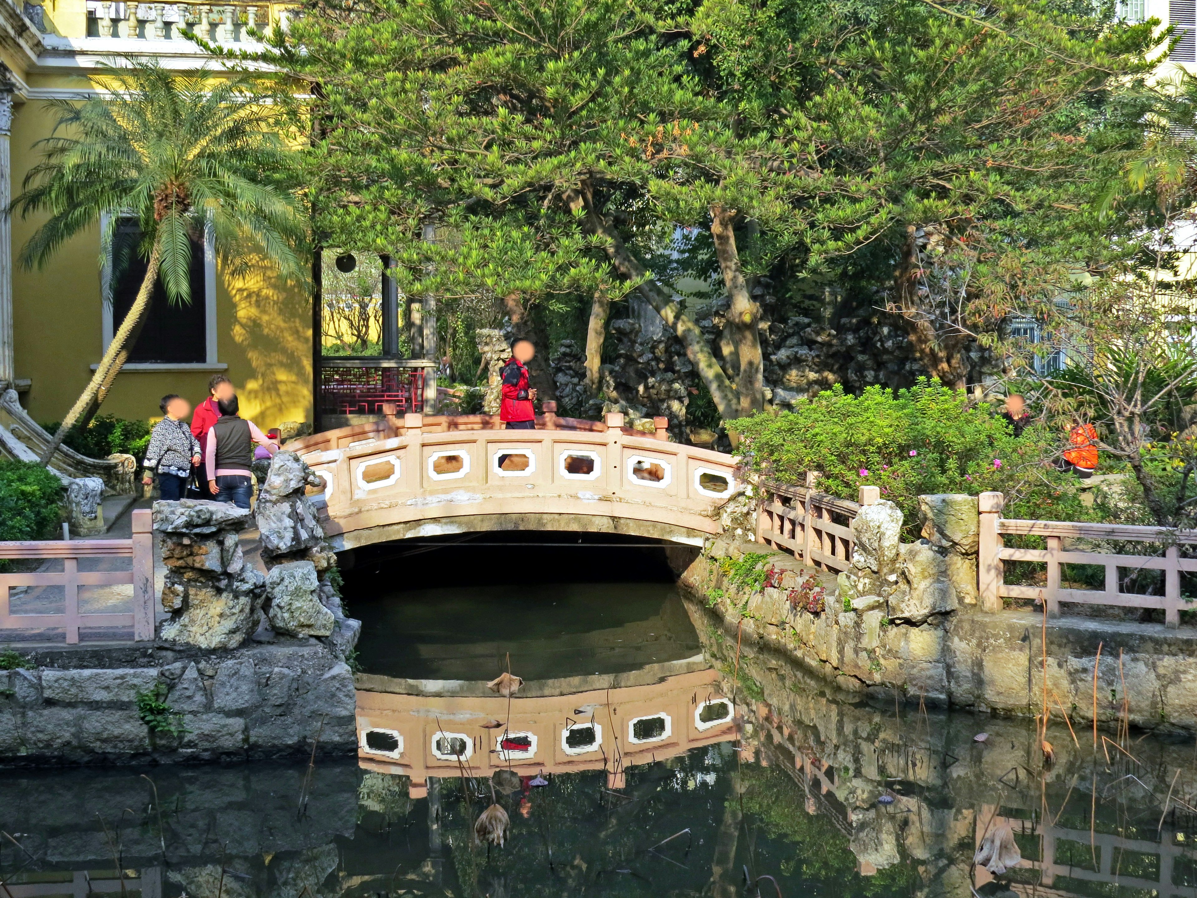 Malersiche Ansicht einer Bogenbrücke über einen ruhigen Teich in einem japanischen Garten